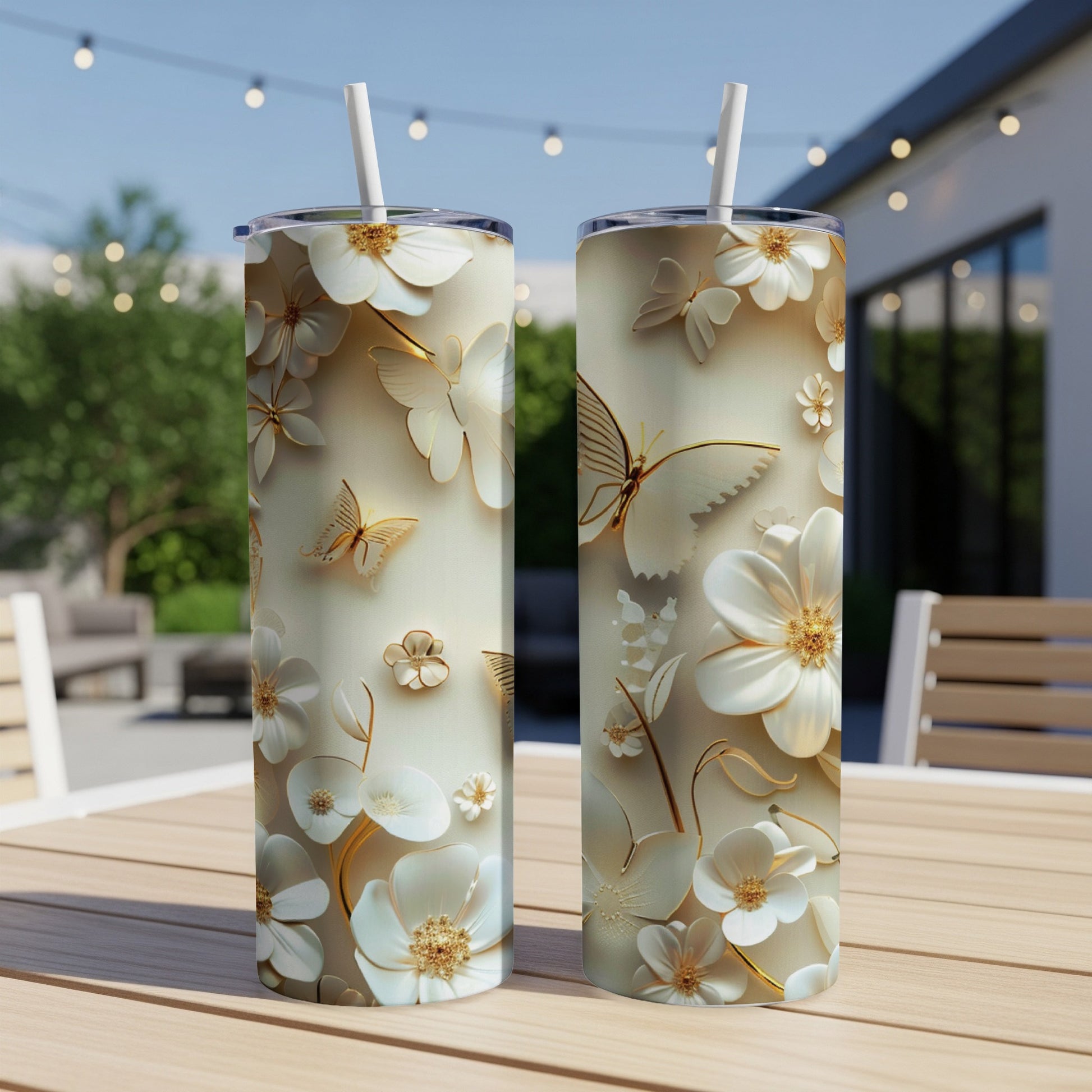 Two tall, slim tumblers with white floral and butterfly designs on a table.
