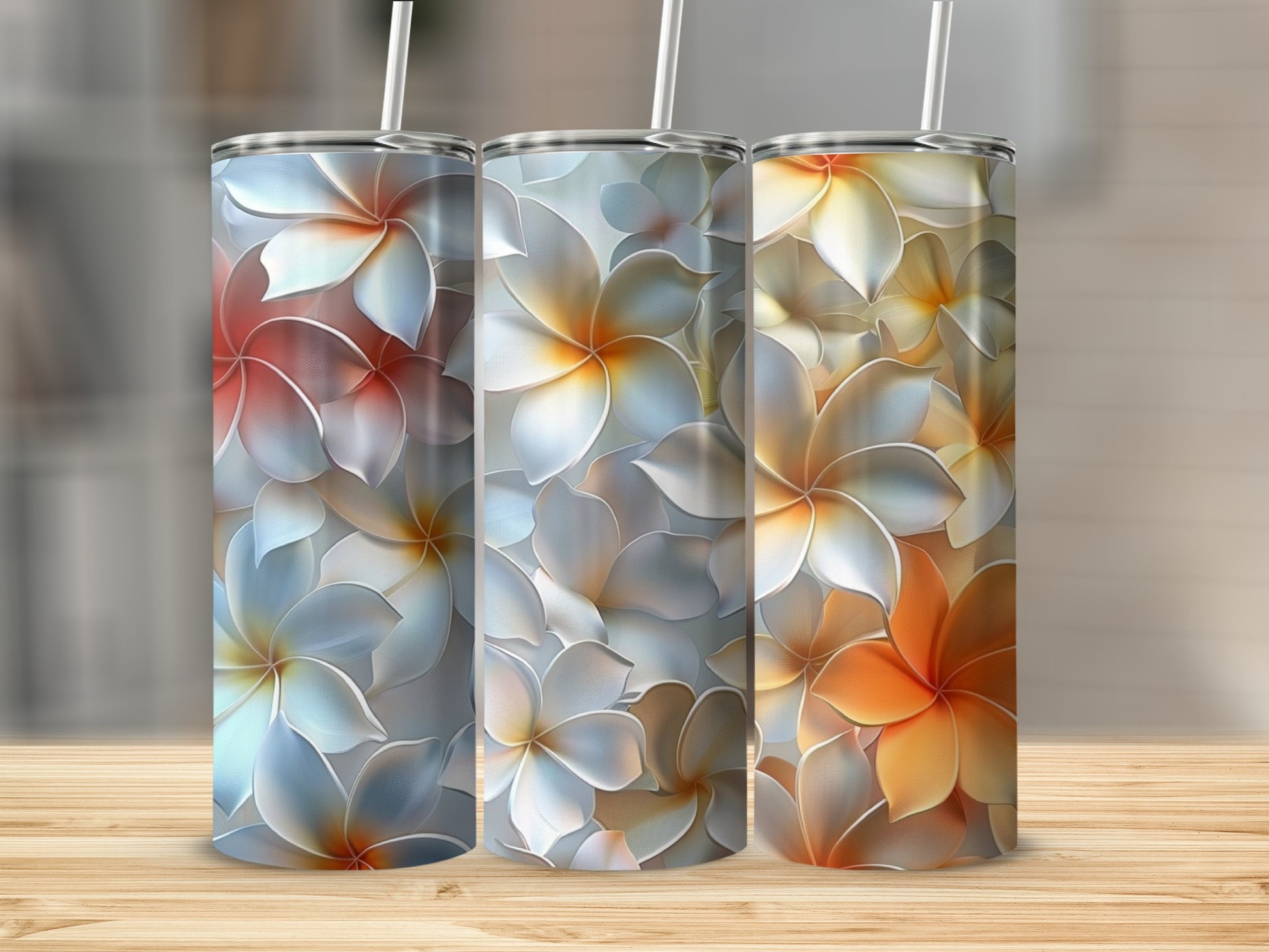 Three tumblers with a floral pattern of plumeria flowers in white, orange, and red hues.