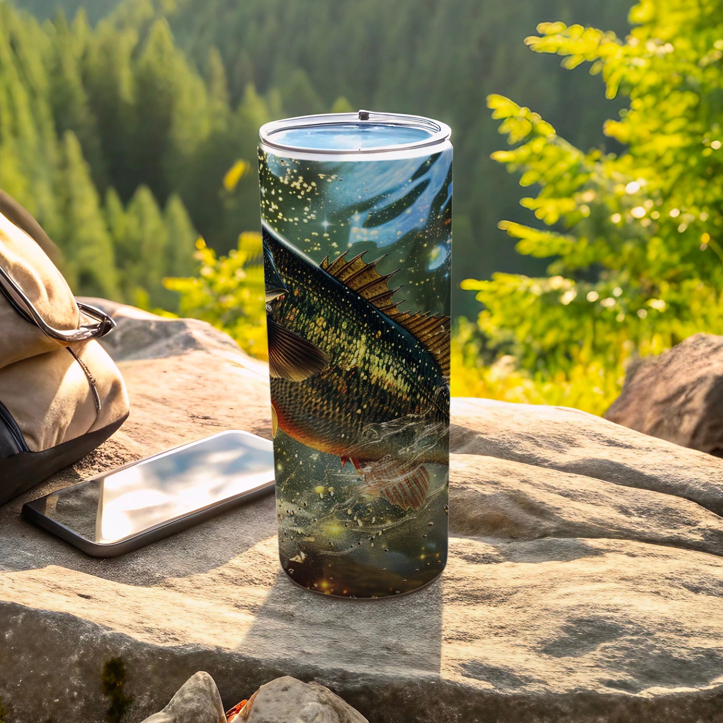 Tall tumbler with jumping fish design sits on rocks, near a backpack and phone.