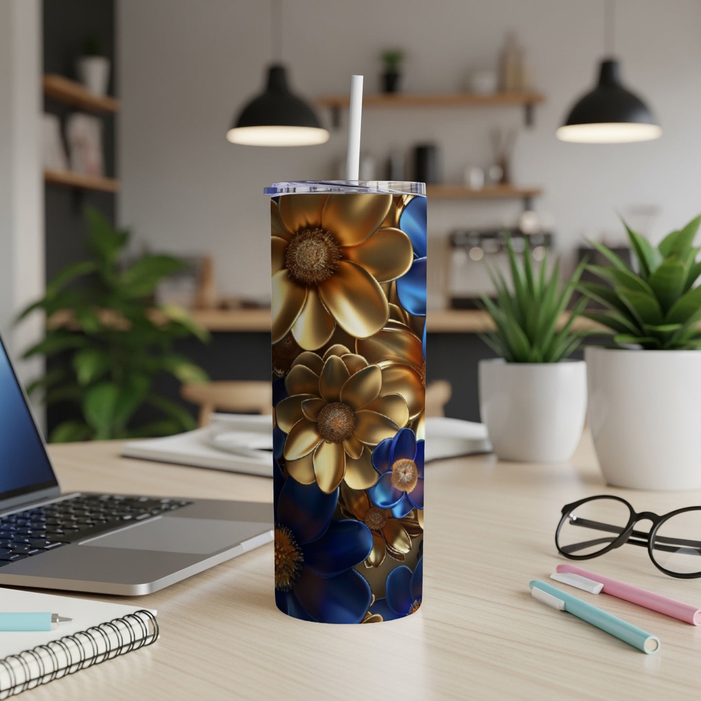 Blue and gold floral tumbler with straw on desk next to laptop.
