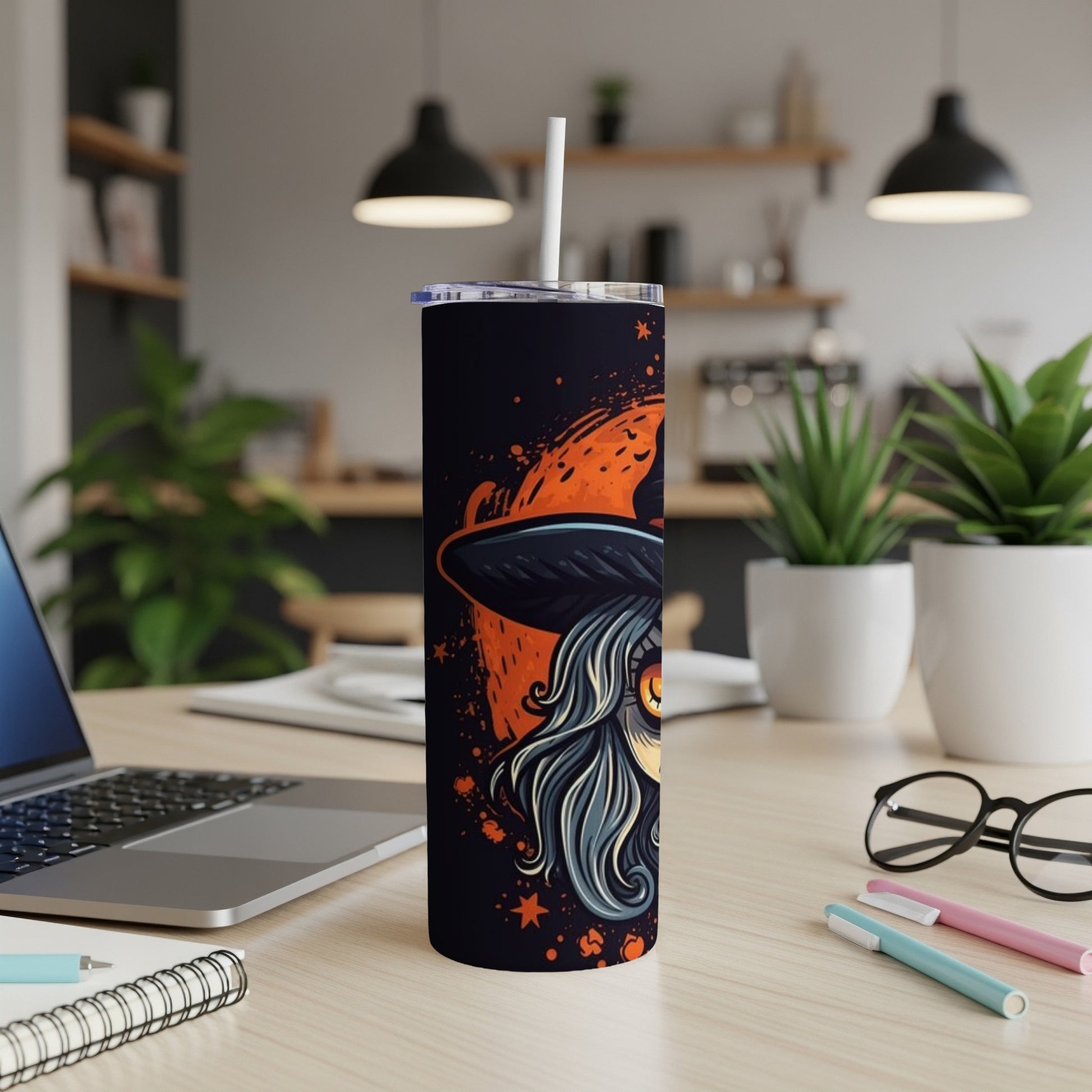 Black tumbler with stylized witch art and orange splashes, featuring a straw.