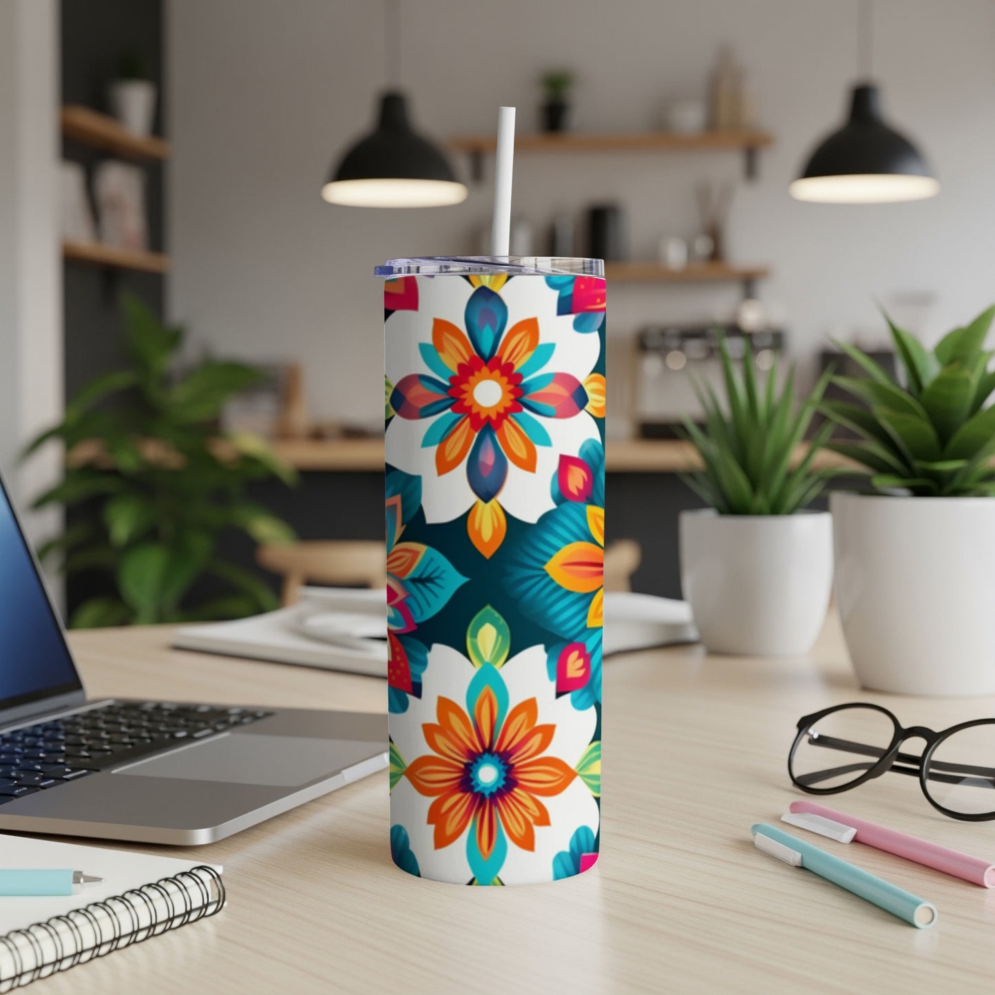 Tall tumbler with colorful floral pattern, white straw, on a desk.