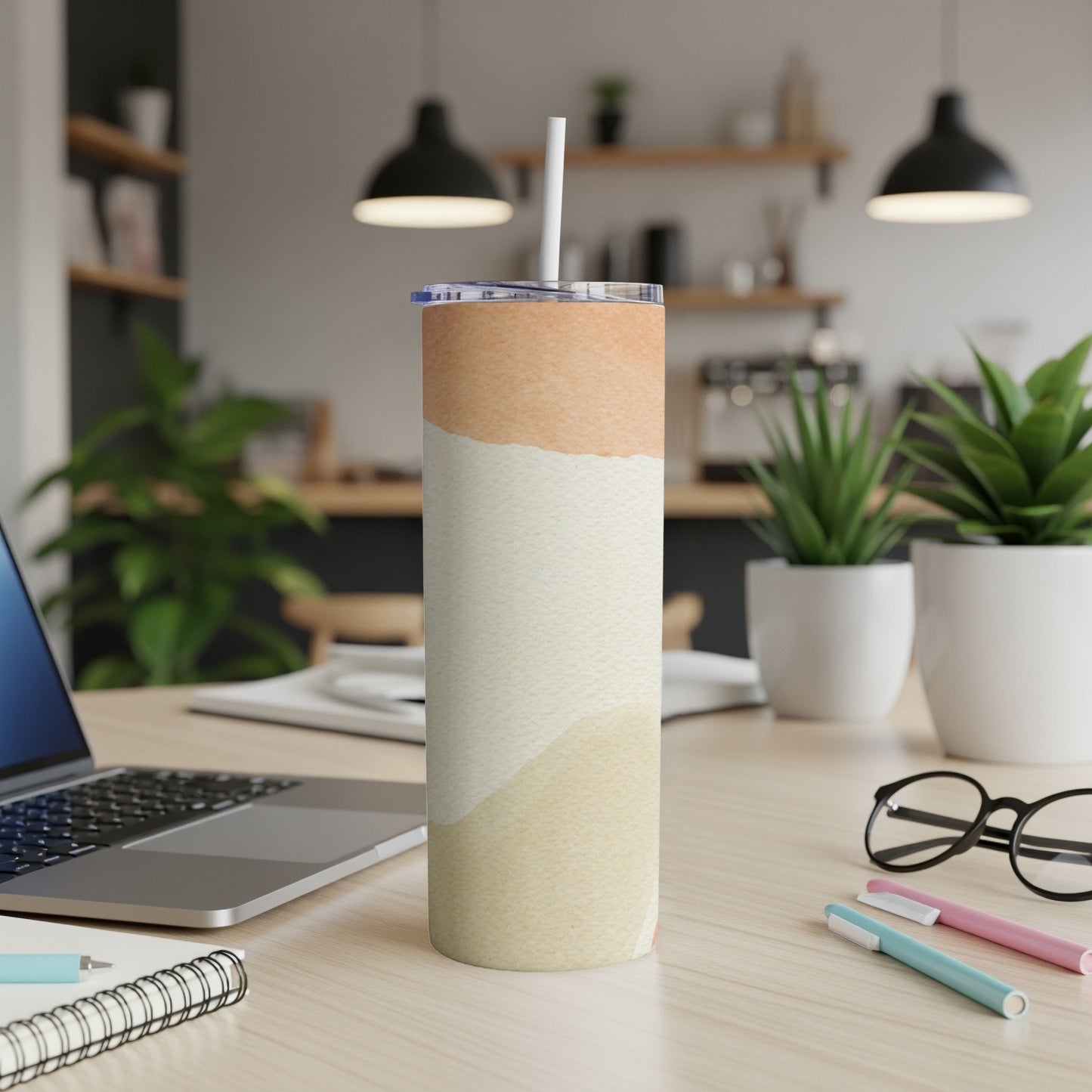 Abstract pastel watercolor tumbler with straw on a desk.