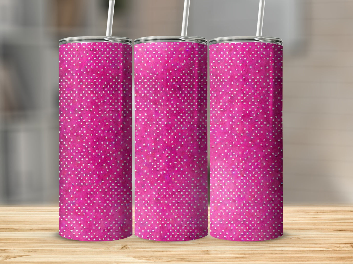 Three pink tumblers with white speckles, resting on a wooden surface.