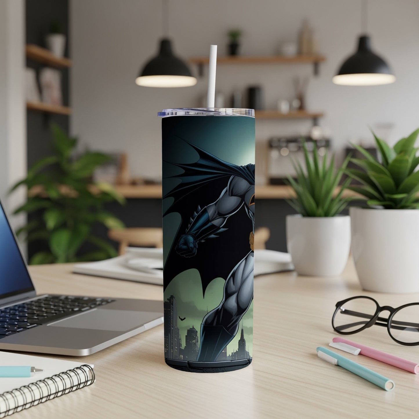 Batman tumbler with cityscape background on desk.