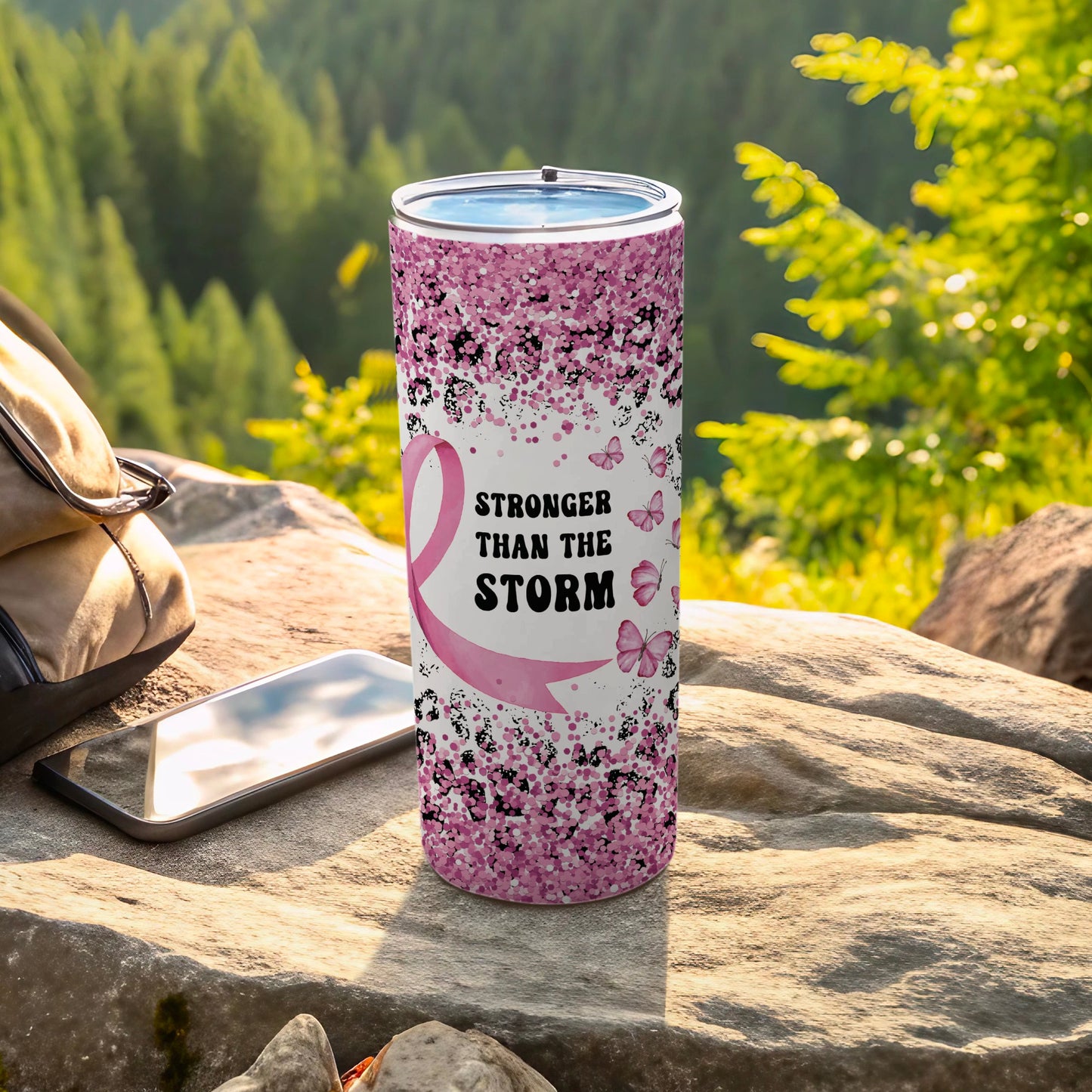 Pink glitter tumbler with ribbon, butterflies, and "Stronger Than the Storm" text.