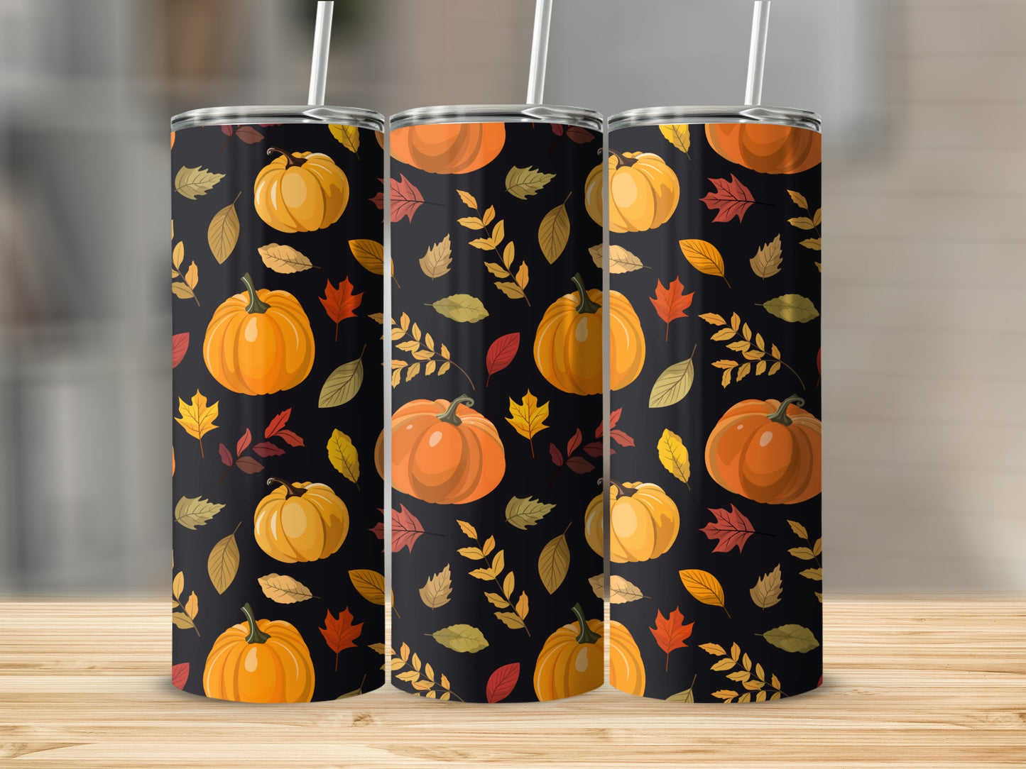 Three tumblers featuring a fall pumpkin and leaf pattern on a wooden surface.