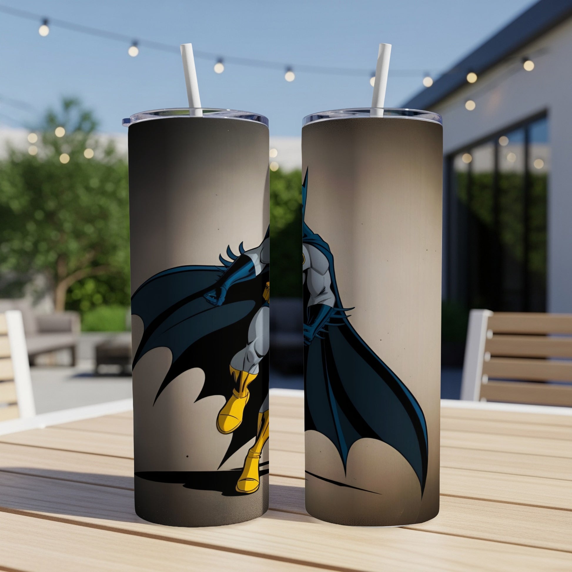 Batman artwork on two tall tumblers with straws, outdoors.