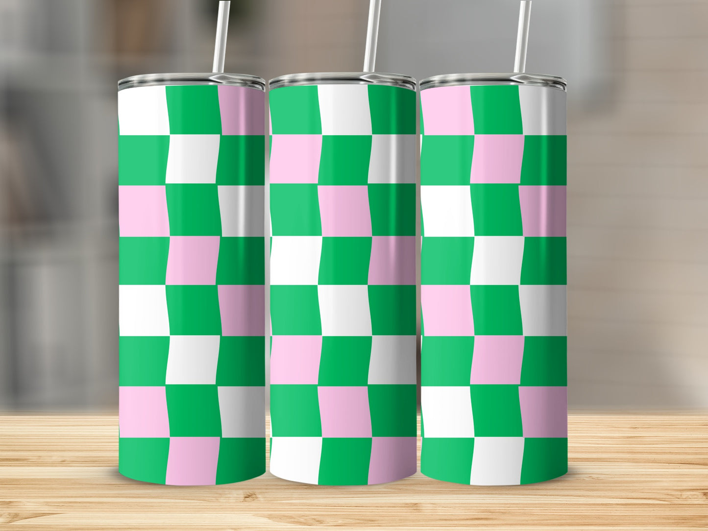Three tumblers with a pink and green checkered pattern and white straws.