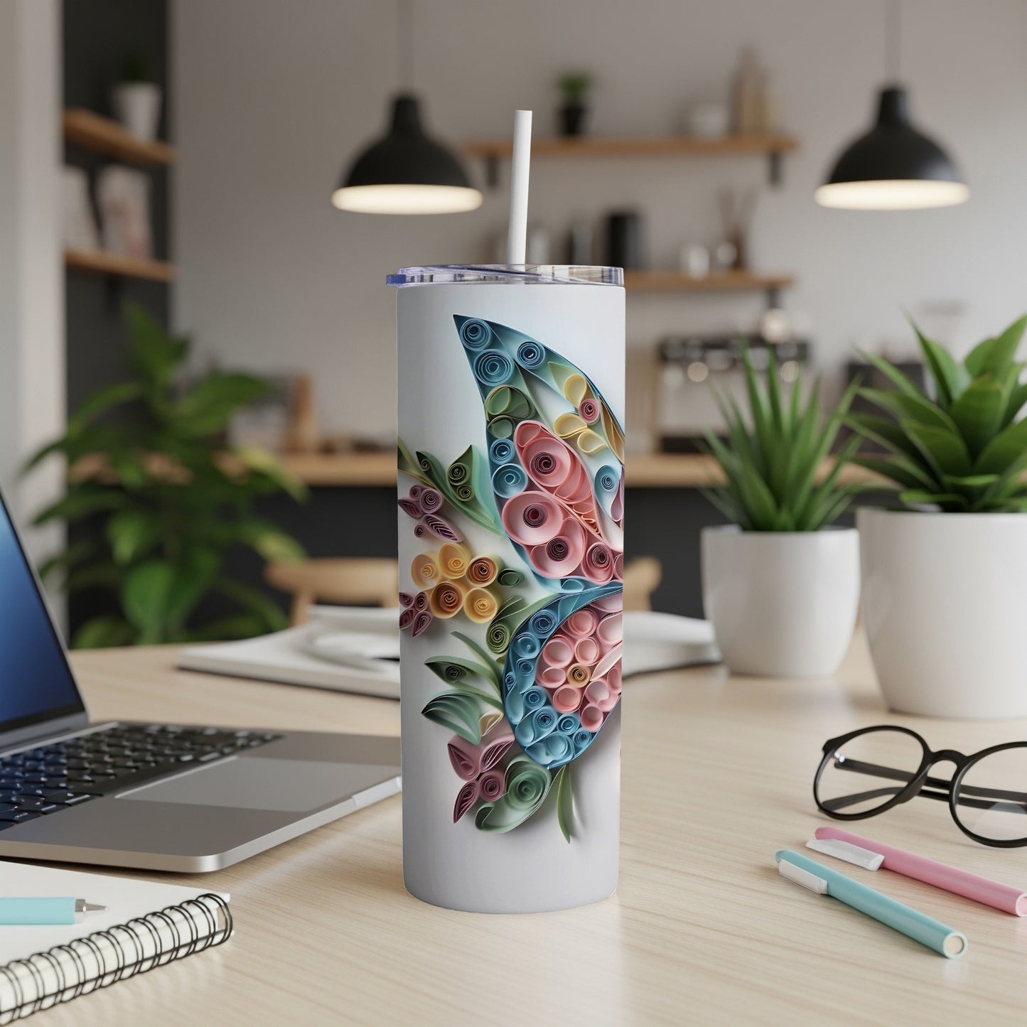 White tumbler with a colorful geometric butterfly made of rolled paper on a desk.