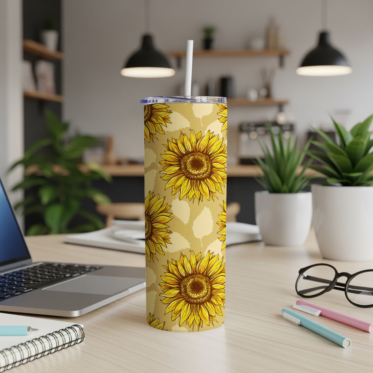 Tall tumbler with a yellow sunflower pattern and a white straw on a wooden desk.