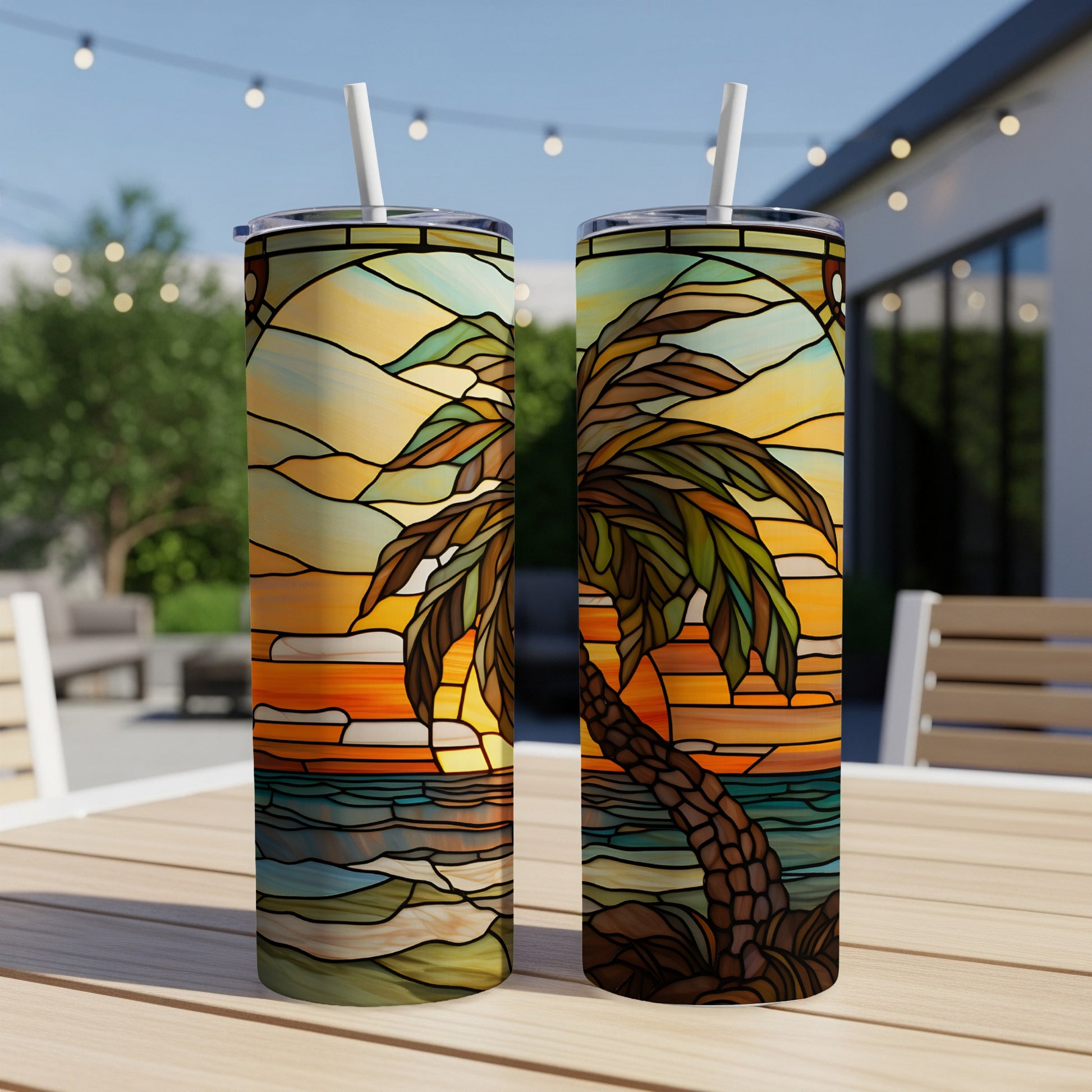 Two tumblers with stained-glass palm tree sunset design on outdoor table.