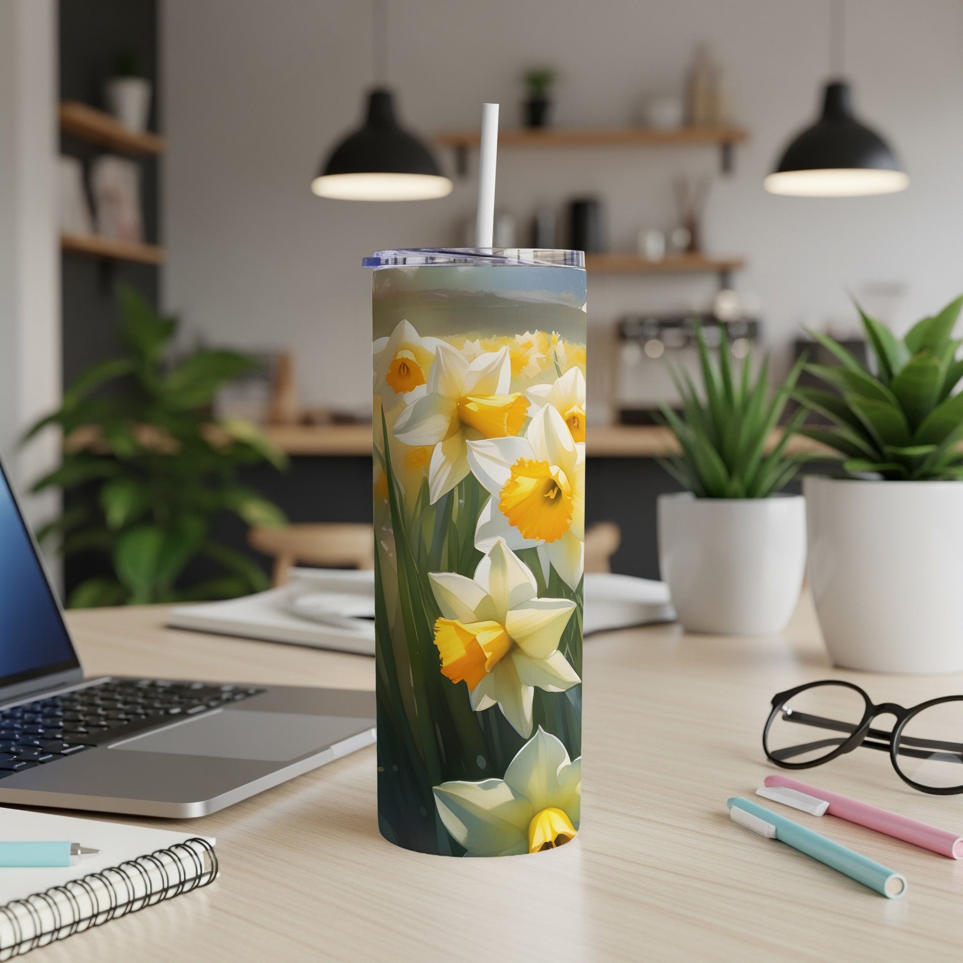 White and yellow daffodils bloom on a white tumbler with a straw.