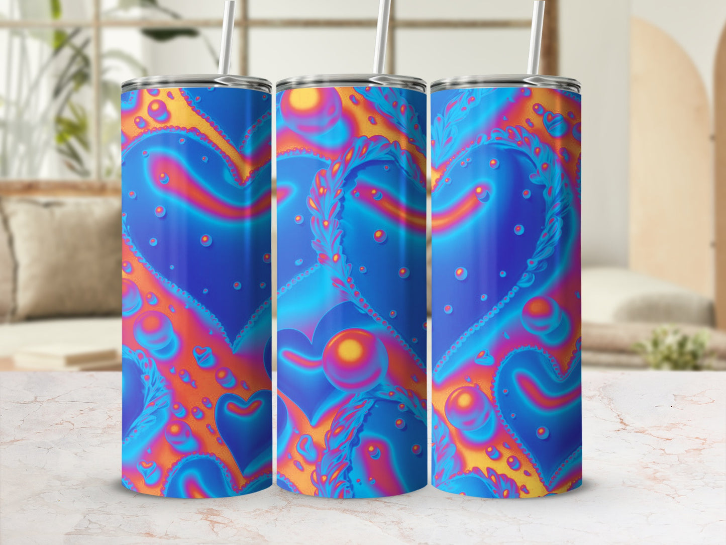 Three blue and orange heart pattern tumblers with straws on a marbled surface.
