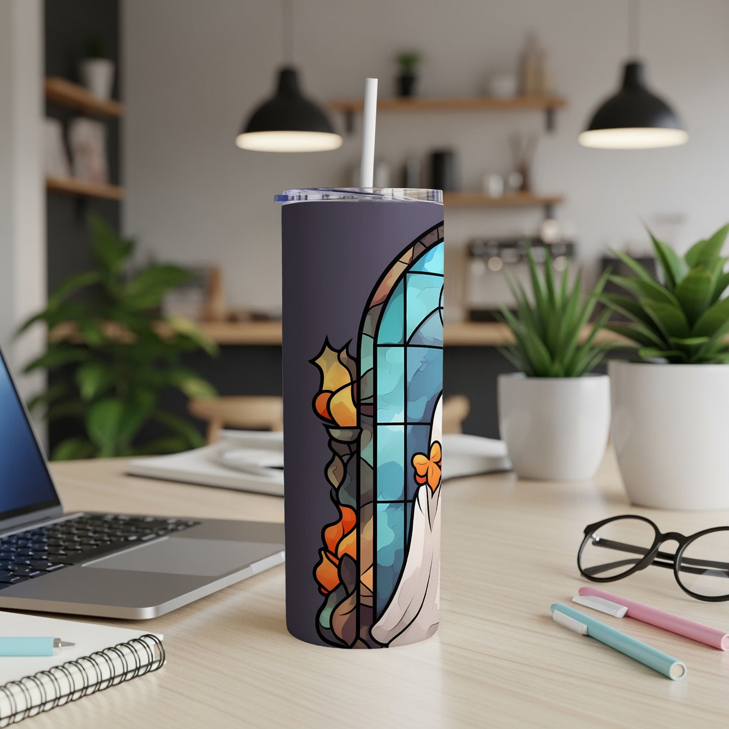 Stained glass ghost tumbler with a straw on a desk.