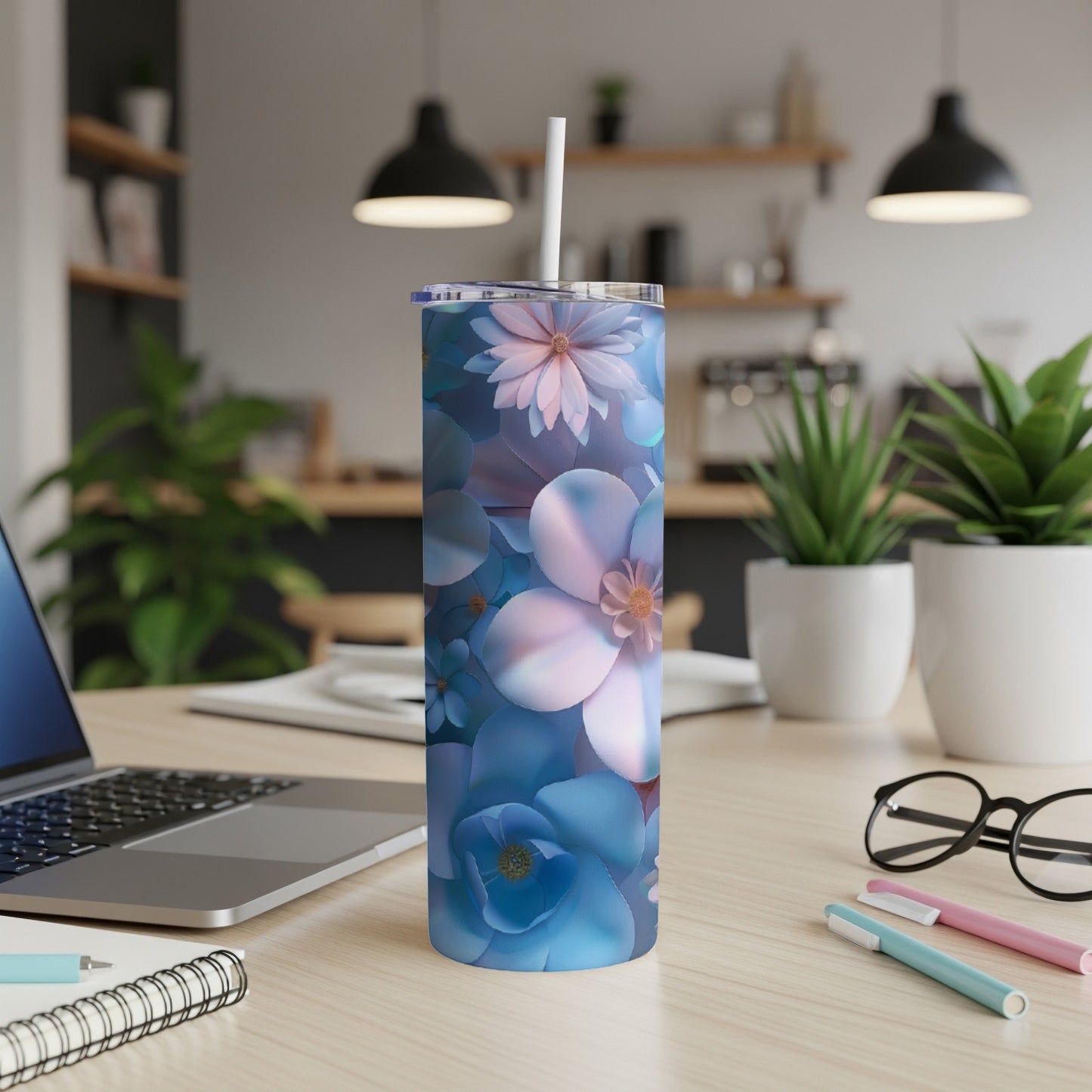 Blue floral patterned skinny tumbler with white straw on a desk.