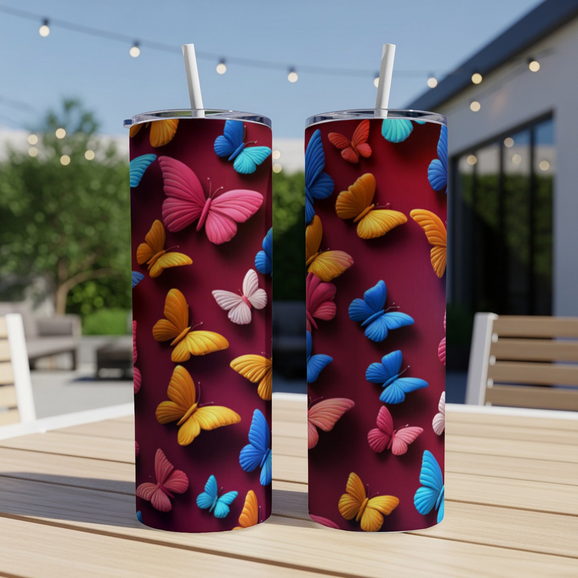Two red tumblers with colorful butterfly patterns on a wooden table.