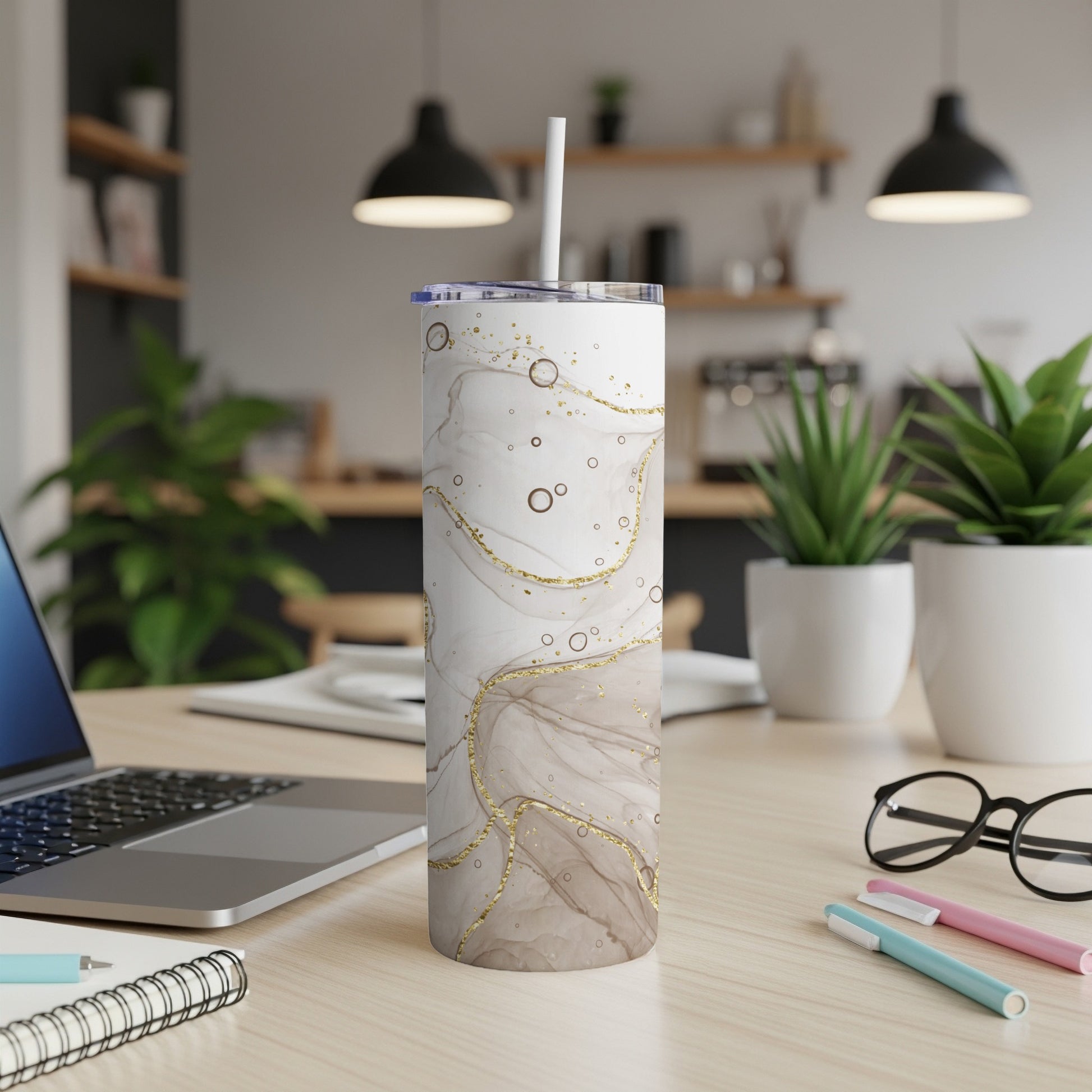 White tumbler with marble and gold swirl pattern and straw.