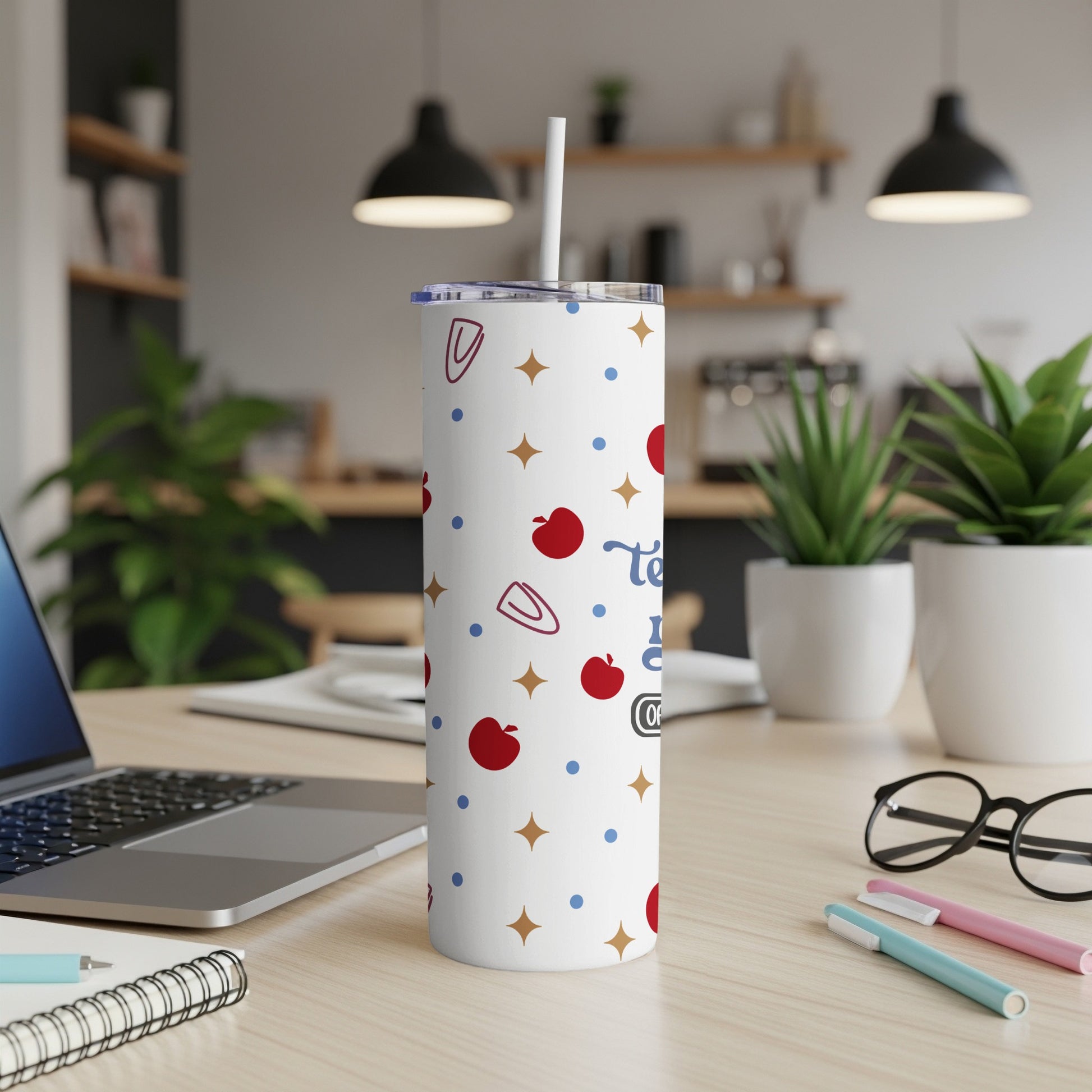 White tumbler with apple and paperclip pattern, "Teach Love Inspire" text.