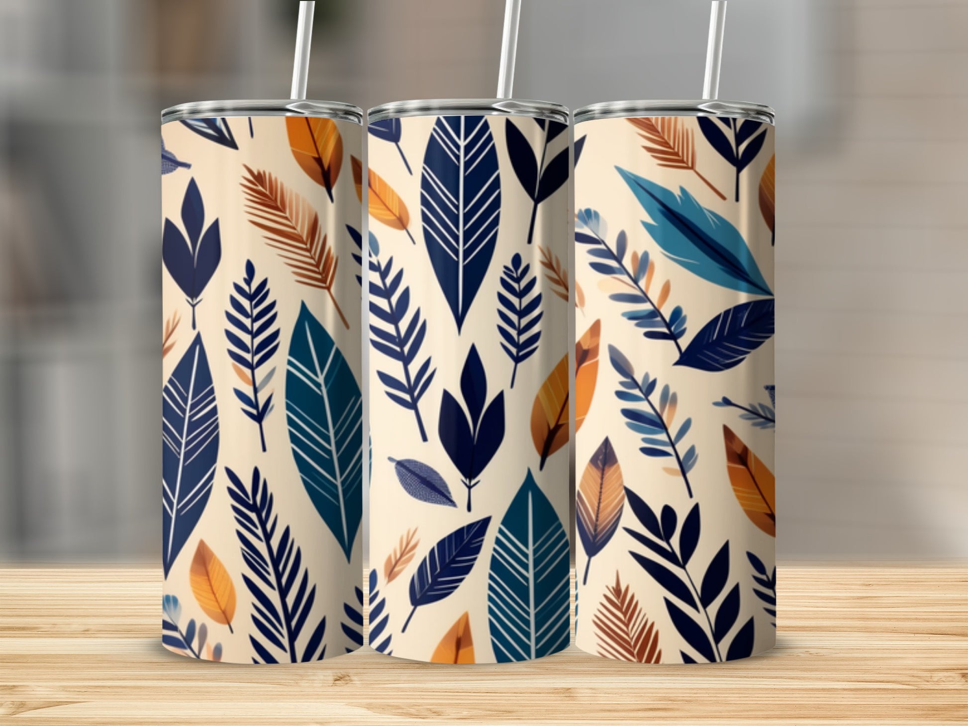 Three tumblers with a repeating pattern of cream, navy, teal, and rust-colored leaves.