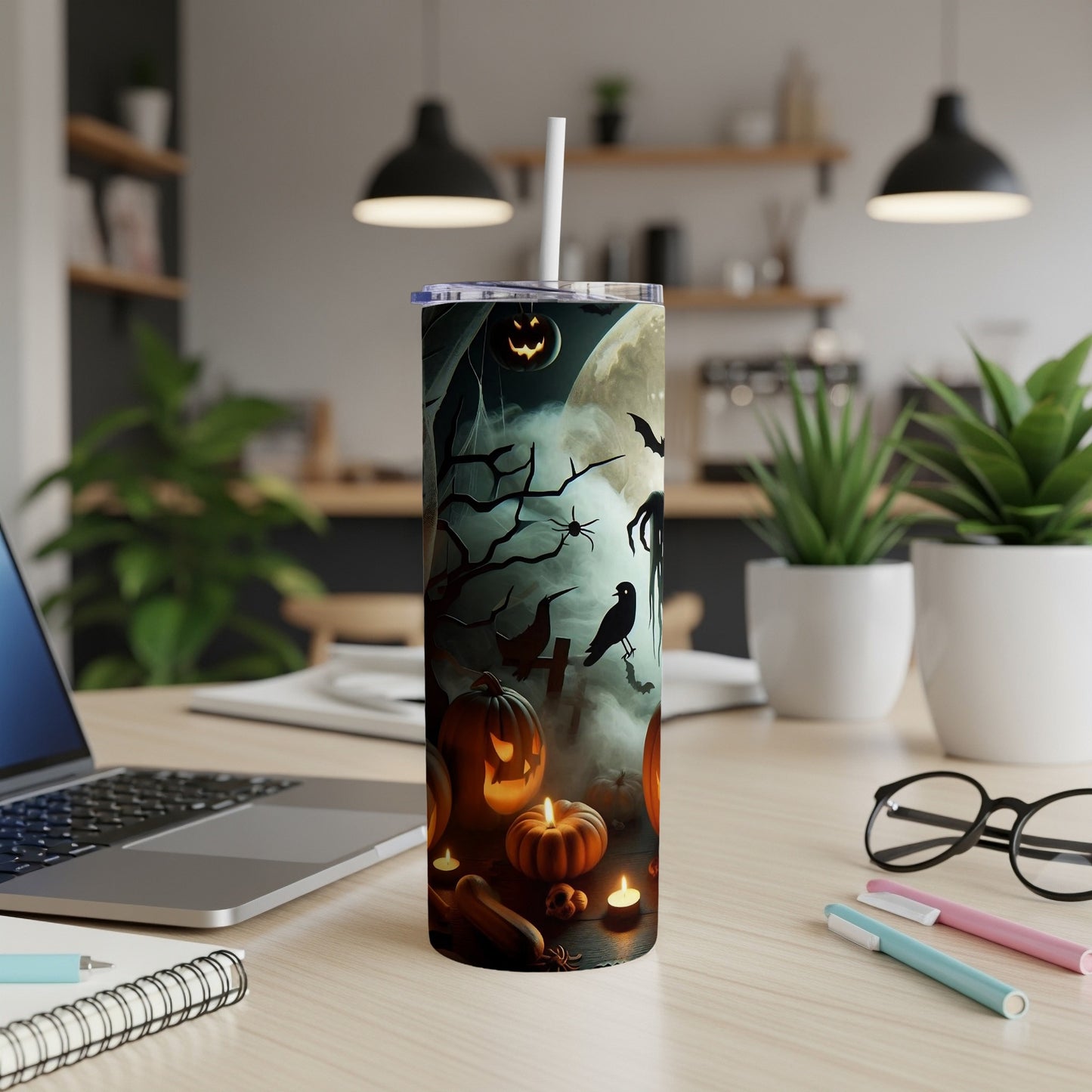 Tumbler with Halloween design featuring pumpkins, ghosts, and bats on a desk.