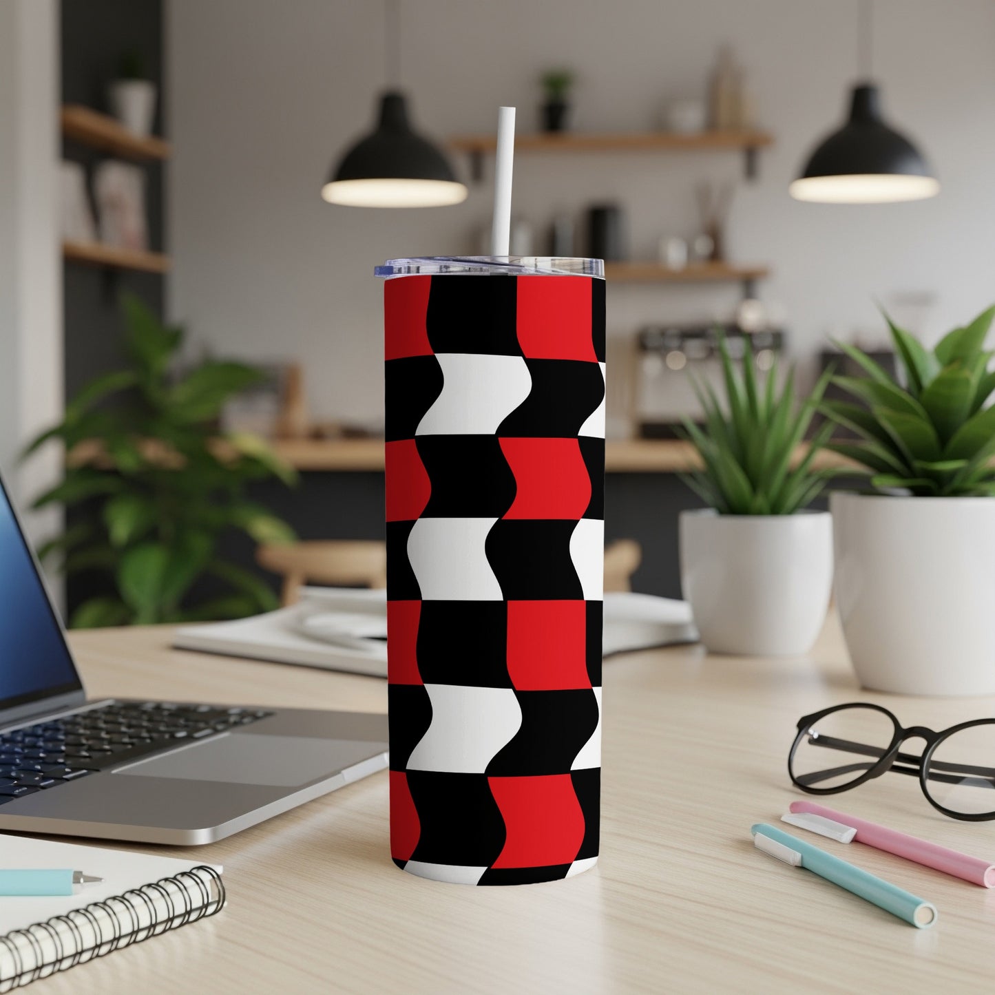 Red, white, and black wavy geometric pattern tumbler on a desk.