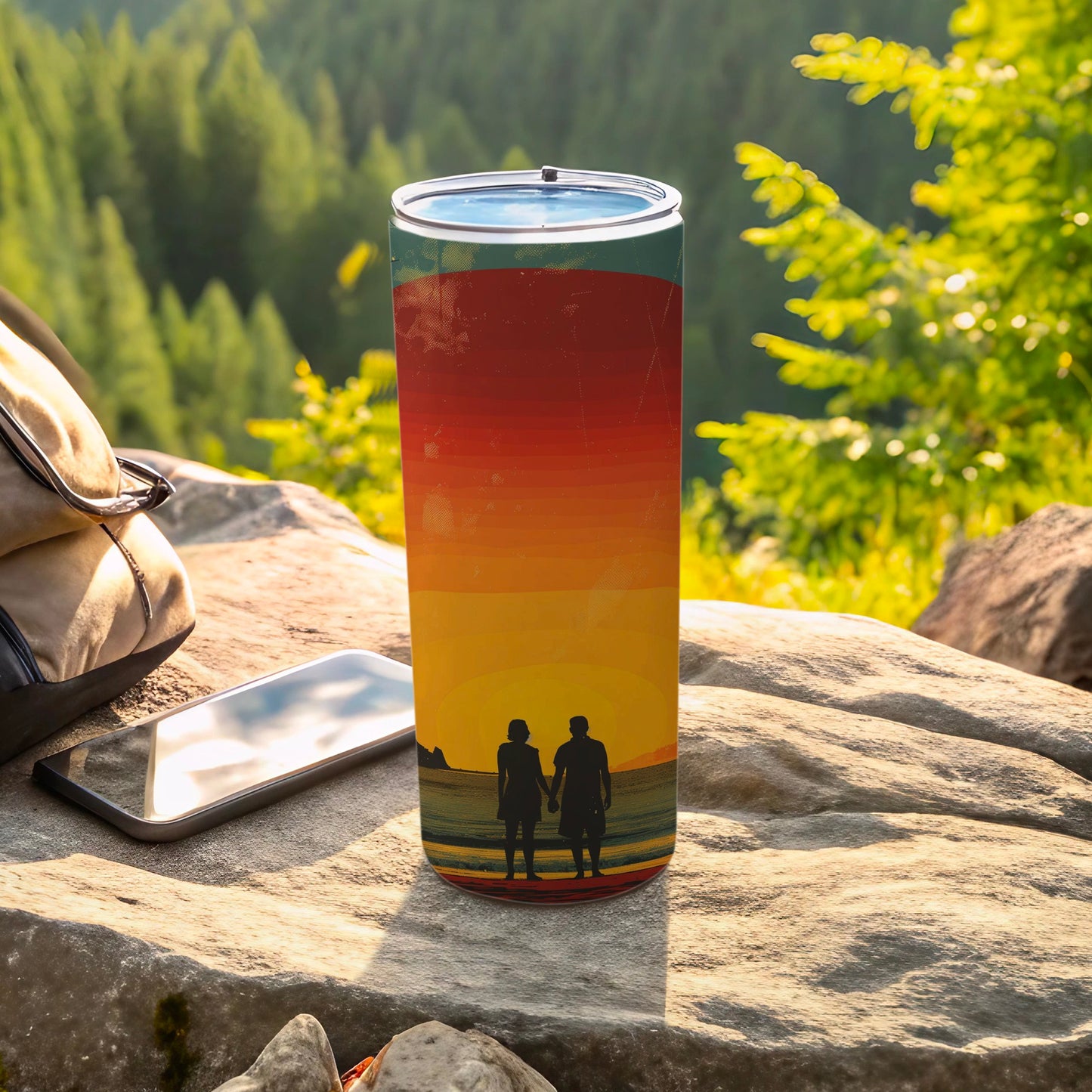 Tumbler with sunset silhouette of couple on beach, backpack, and phone.