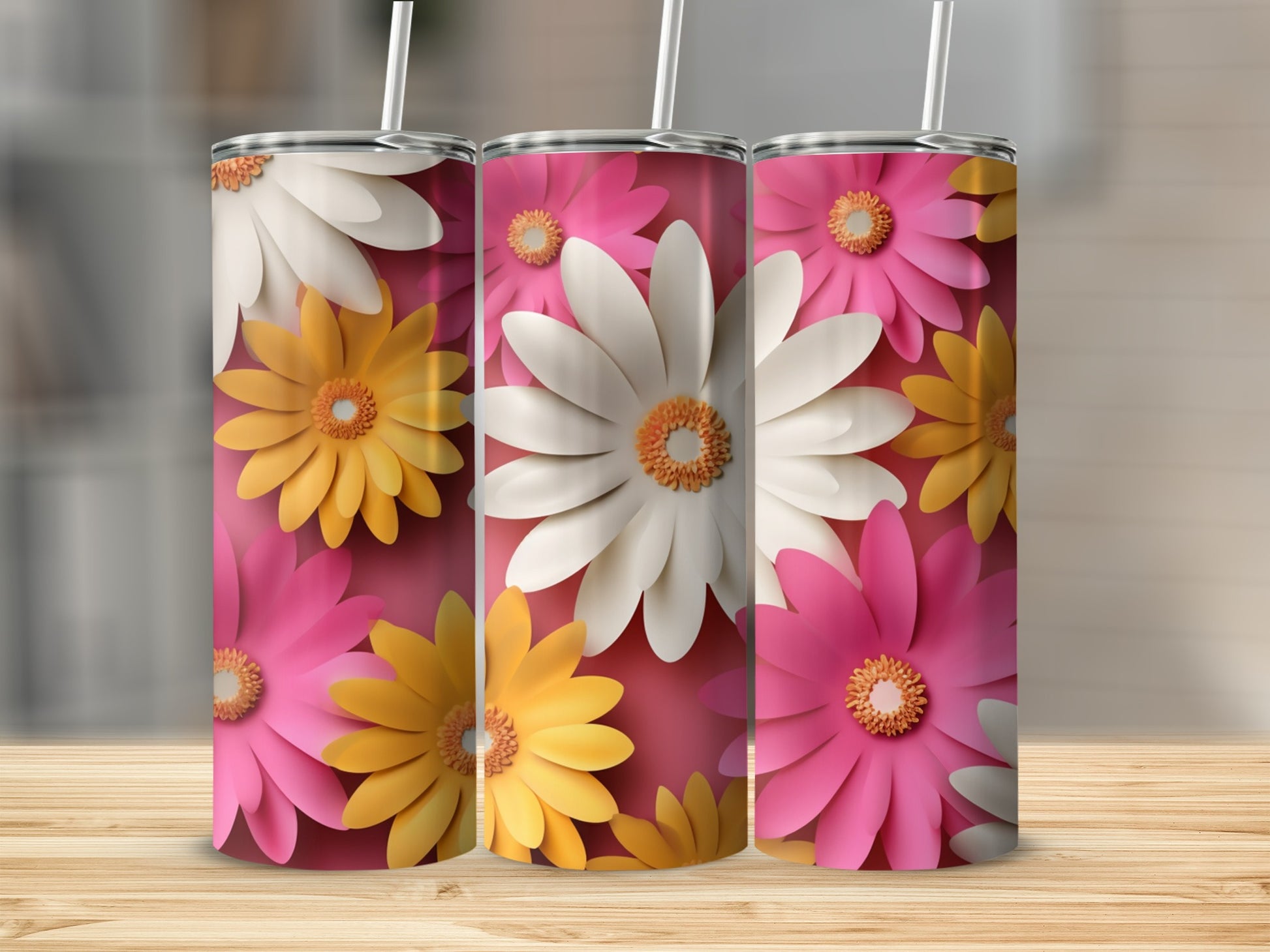 Three floral tumblers with pink, white, and yellow daisies on a wooden surface.