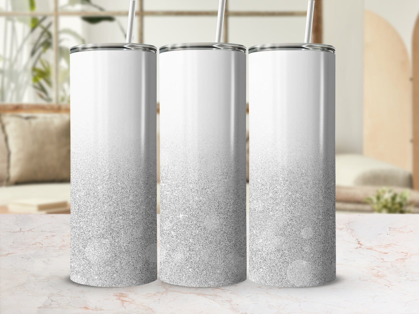 Three white tumblers with silver glitter gradient stand on a marble countertop.