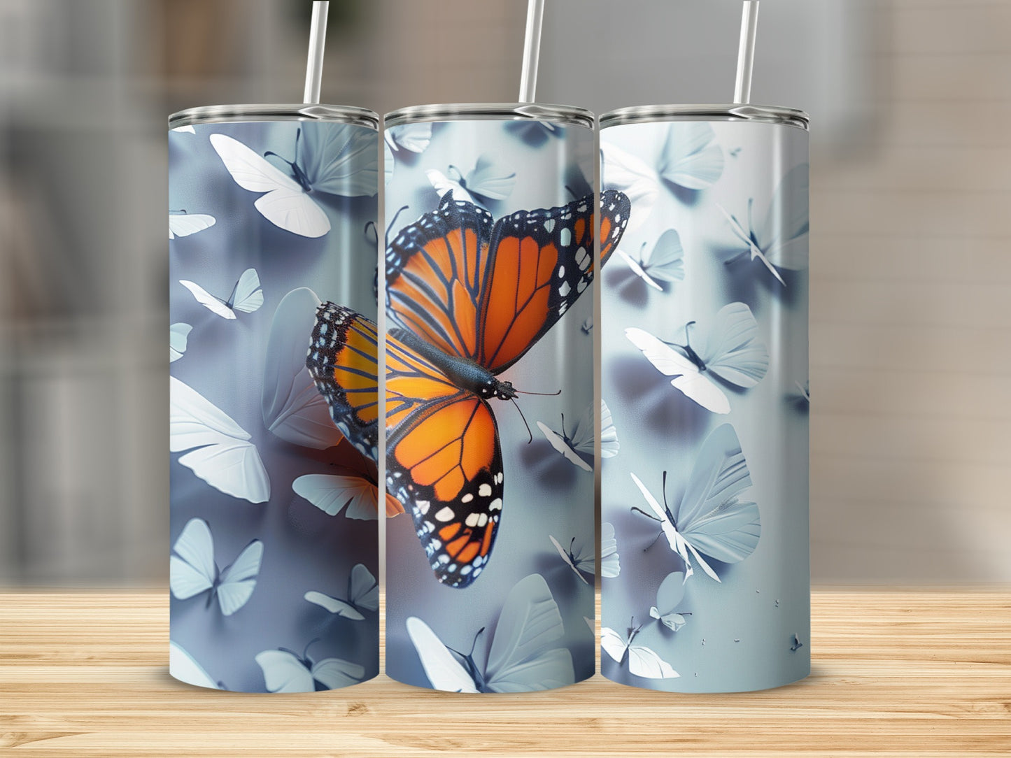 Three tumblers with monarch and blue butterflies on a wooden surface.