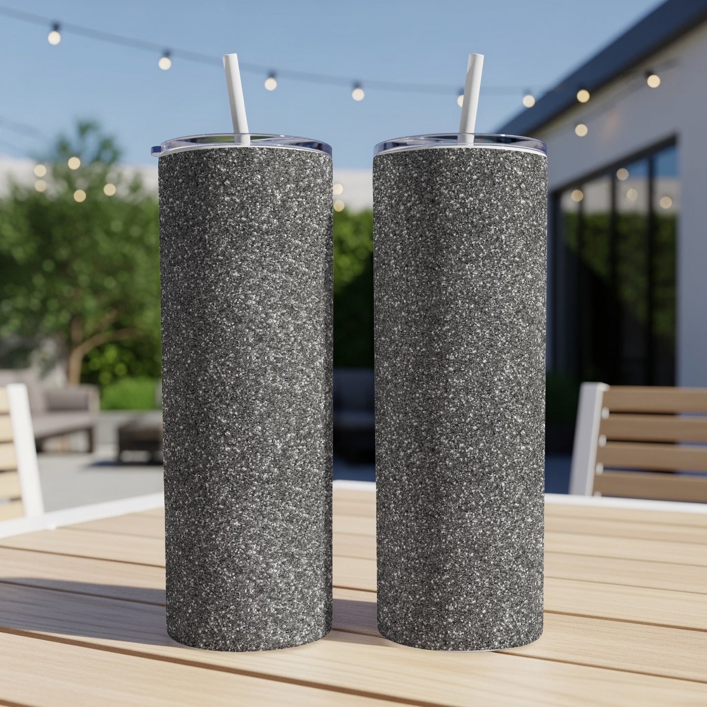Two glitter-textured tumblers with white straws sit on a wooden table.