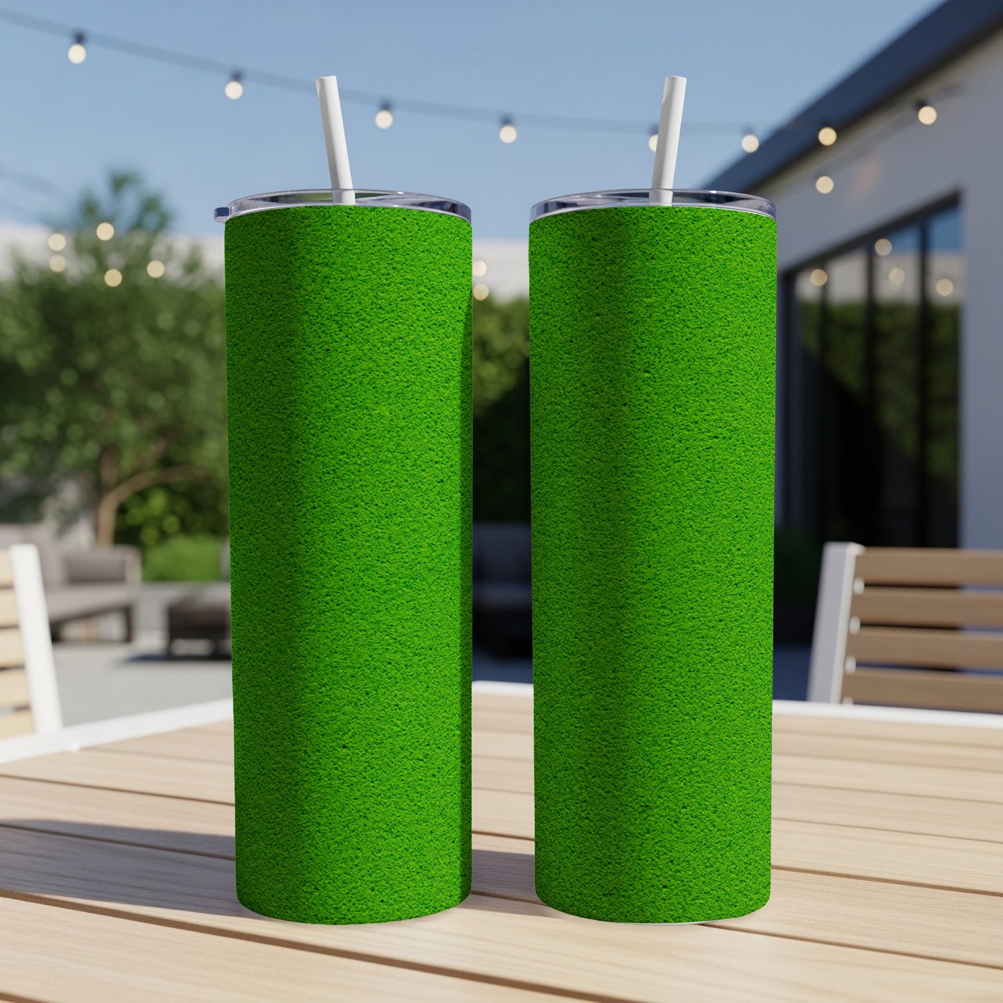 Two green tumblers with white straws stand on a wooden table outdoors.