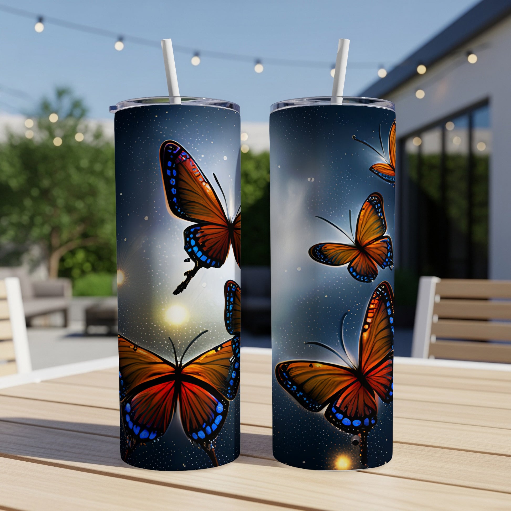 Two tumblers with a vibrant orange butterfly design sit on a wooden table outdoors.