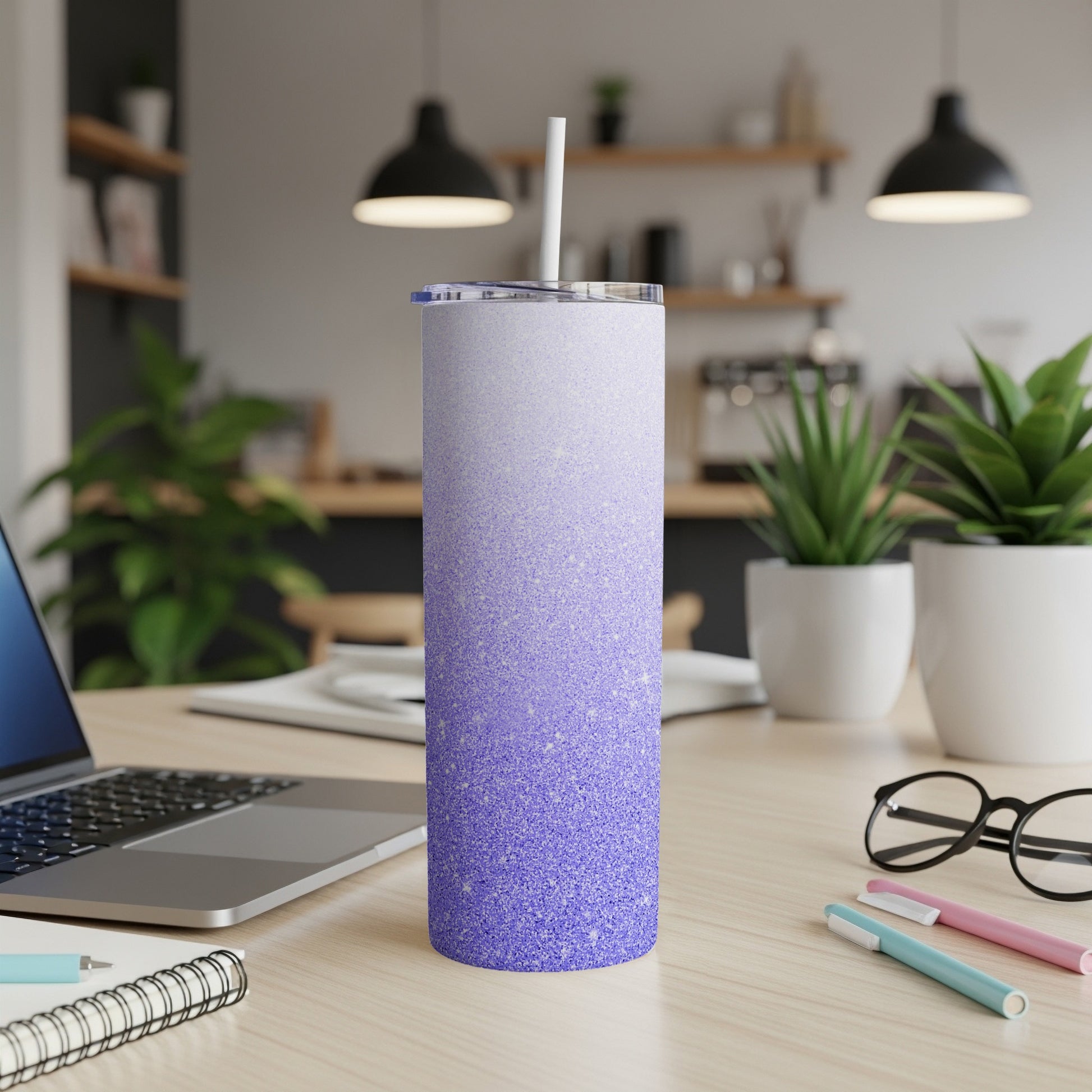 Purple glitter ombre tumbler with straw on a desk.