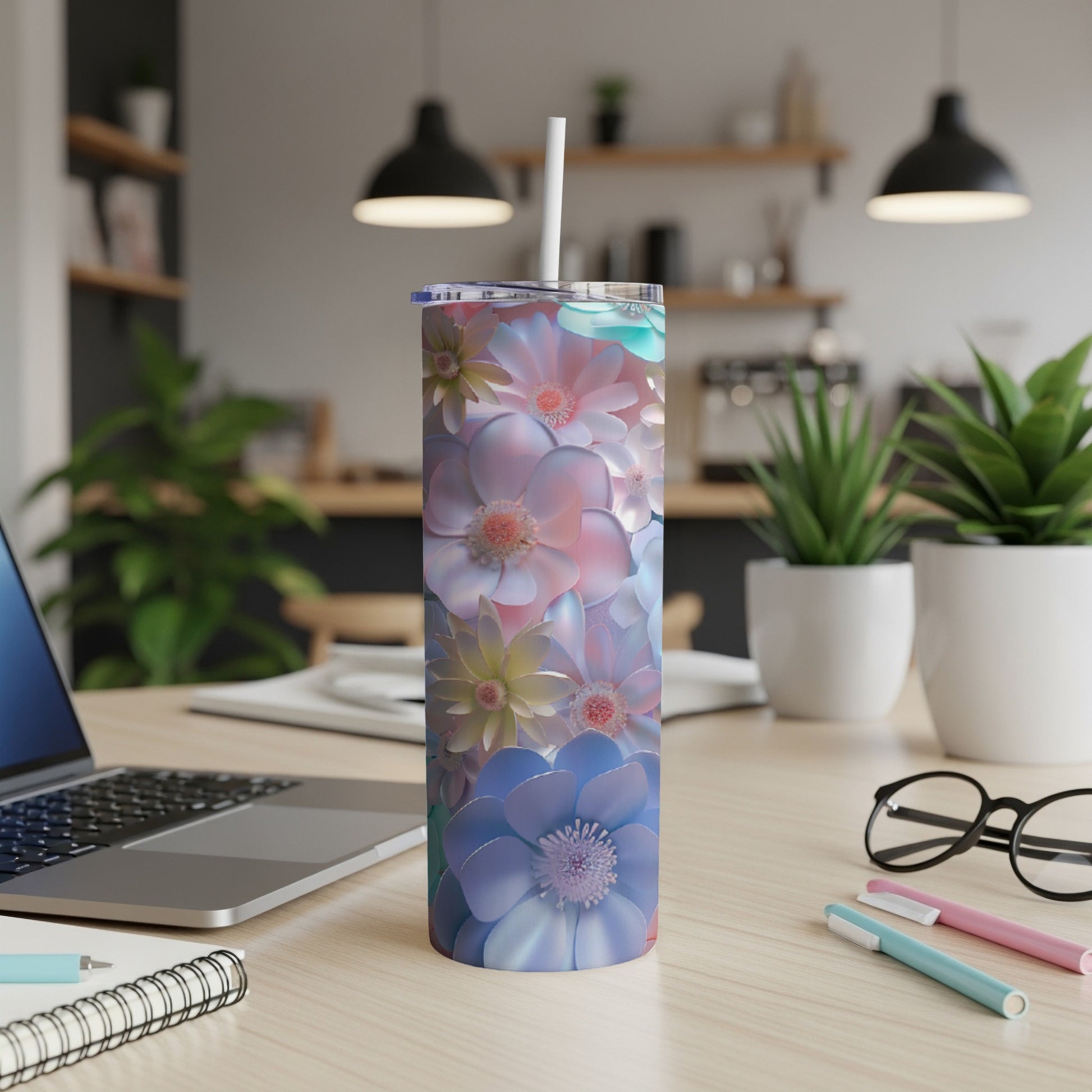 Floral print tumbler with straw on a desk next to a laptop.