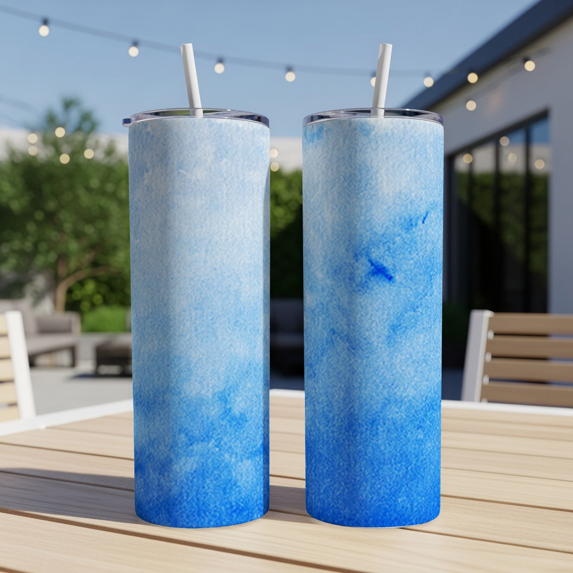 Two tall, slim tumblers with a blue watercolor pattern sit on a wooden table.
