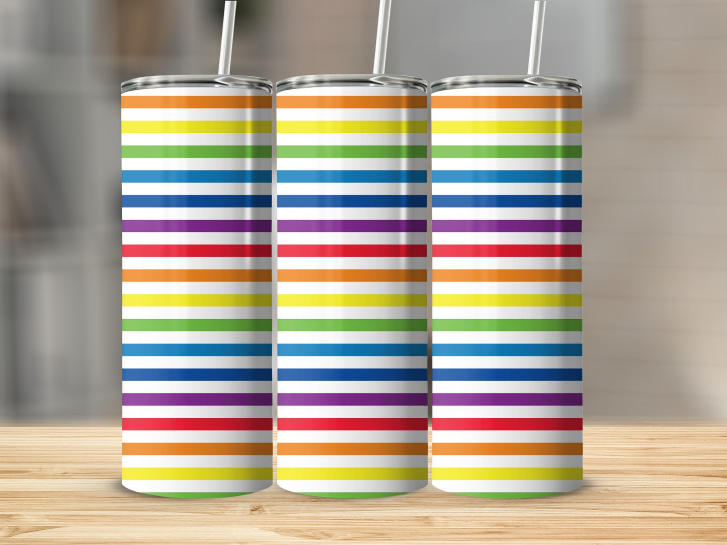 Three tall tumblers with rainbow stripe patterns stand side-by-side on a wooden surface.