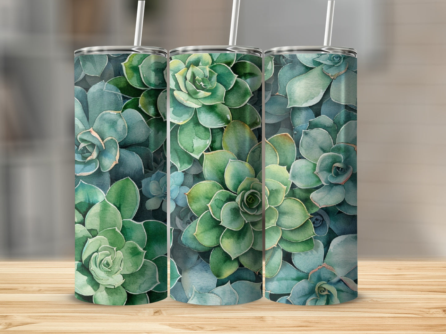 Three tumblers with a watercolor succulent pattern on a wooden surface.