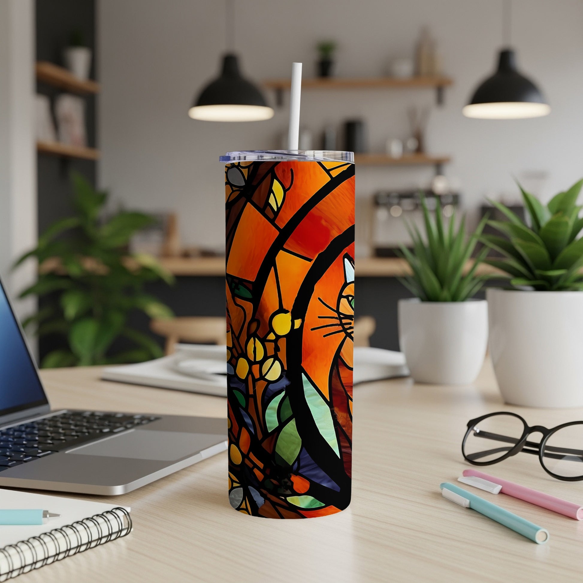 Stained glass-style tumbler with cat design on a desk.