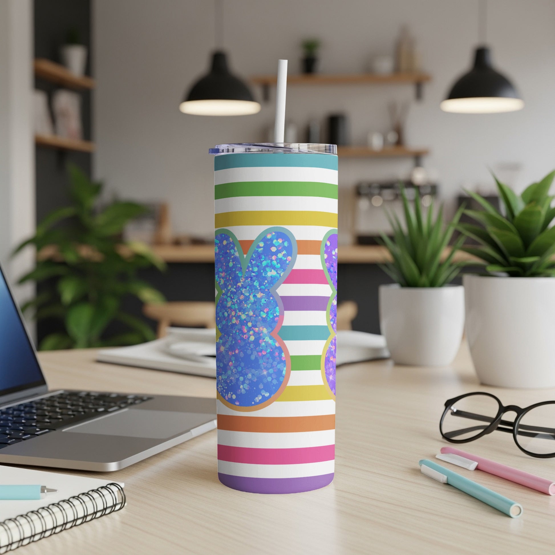 Glittering blue bunny tumbler with rainbow stripes and white straw.