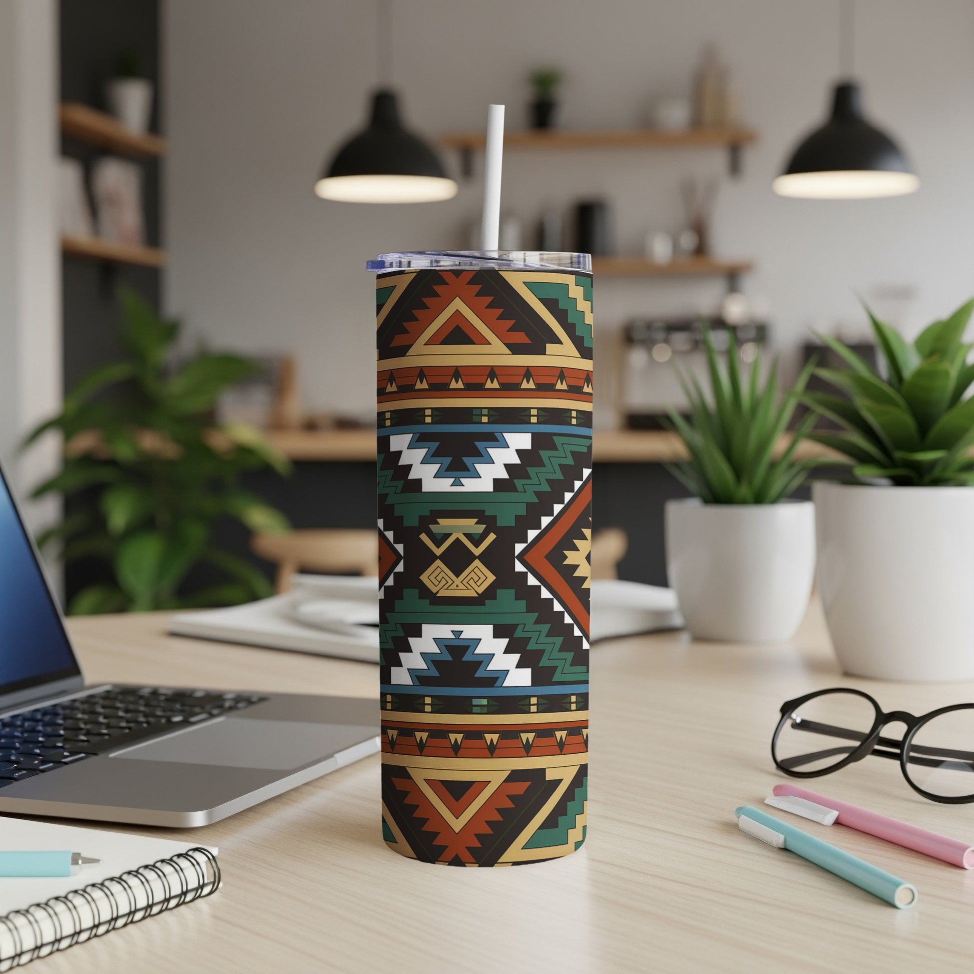 Tribal pattern tumbler with straw on desk next to laptop and pens.
