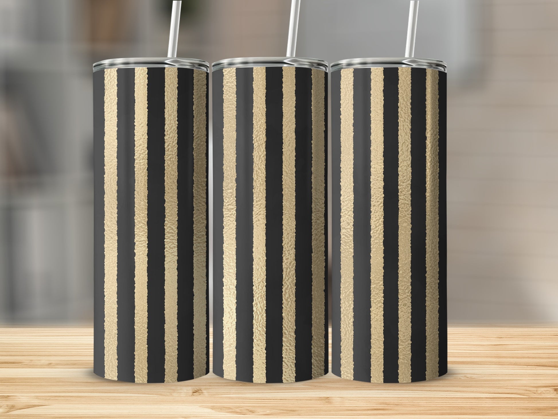Three tall tumblers with black and textured gold stripes on a wooden surface.