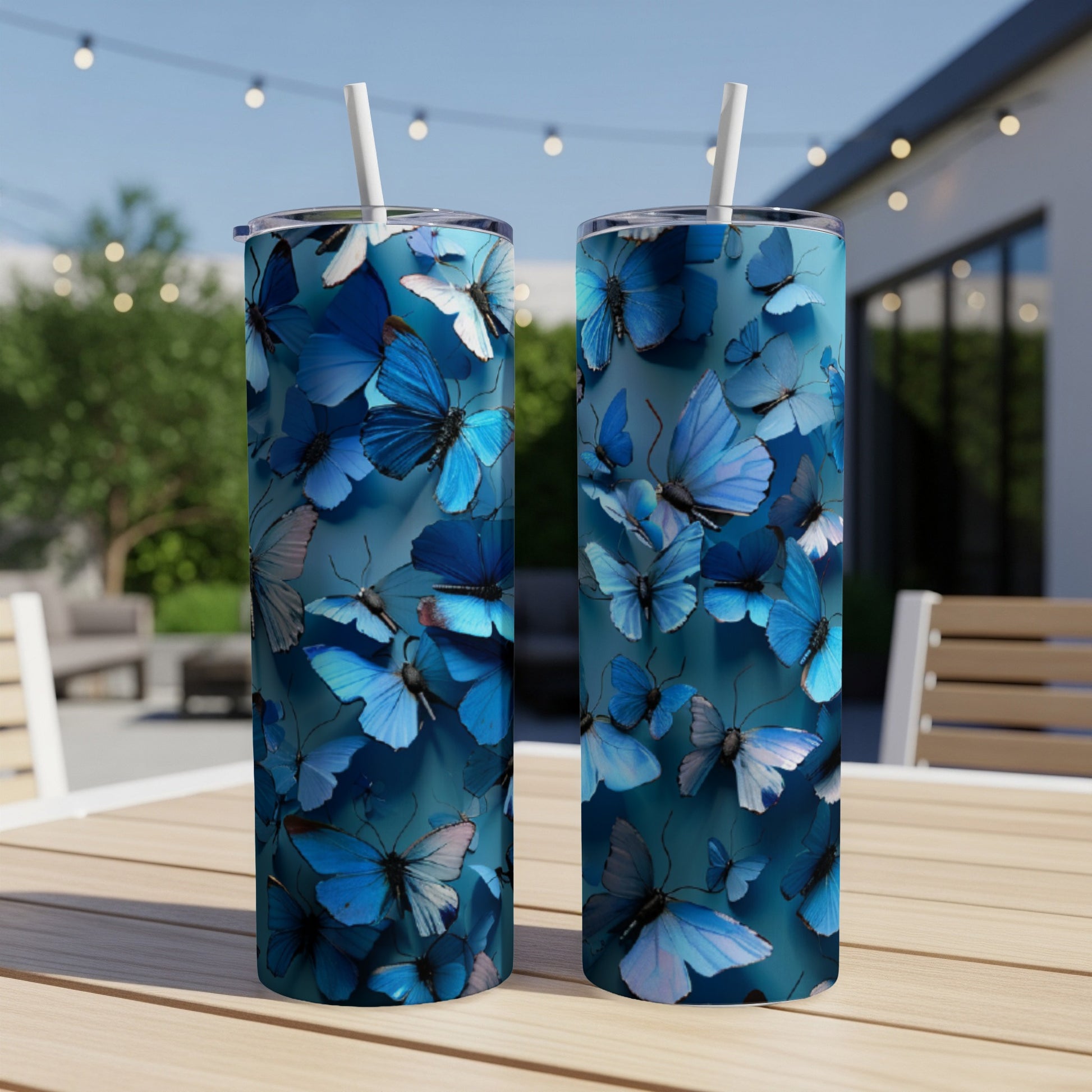 Two blue butterfly tumblers with straws on a wooden table.