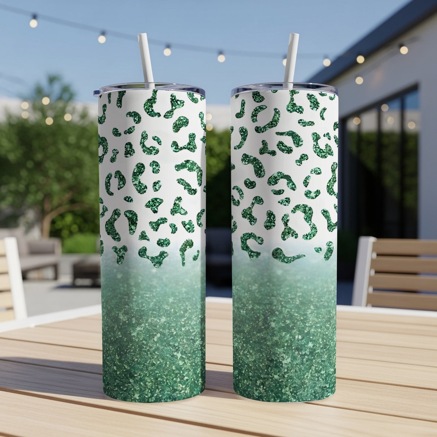Two green glitter leopard print tumblers with straws on a wooden table.