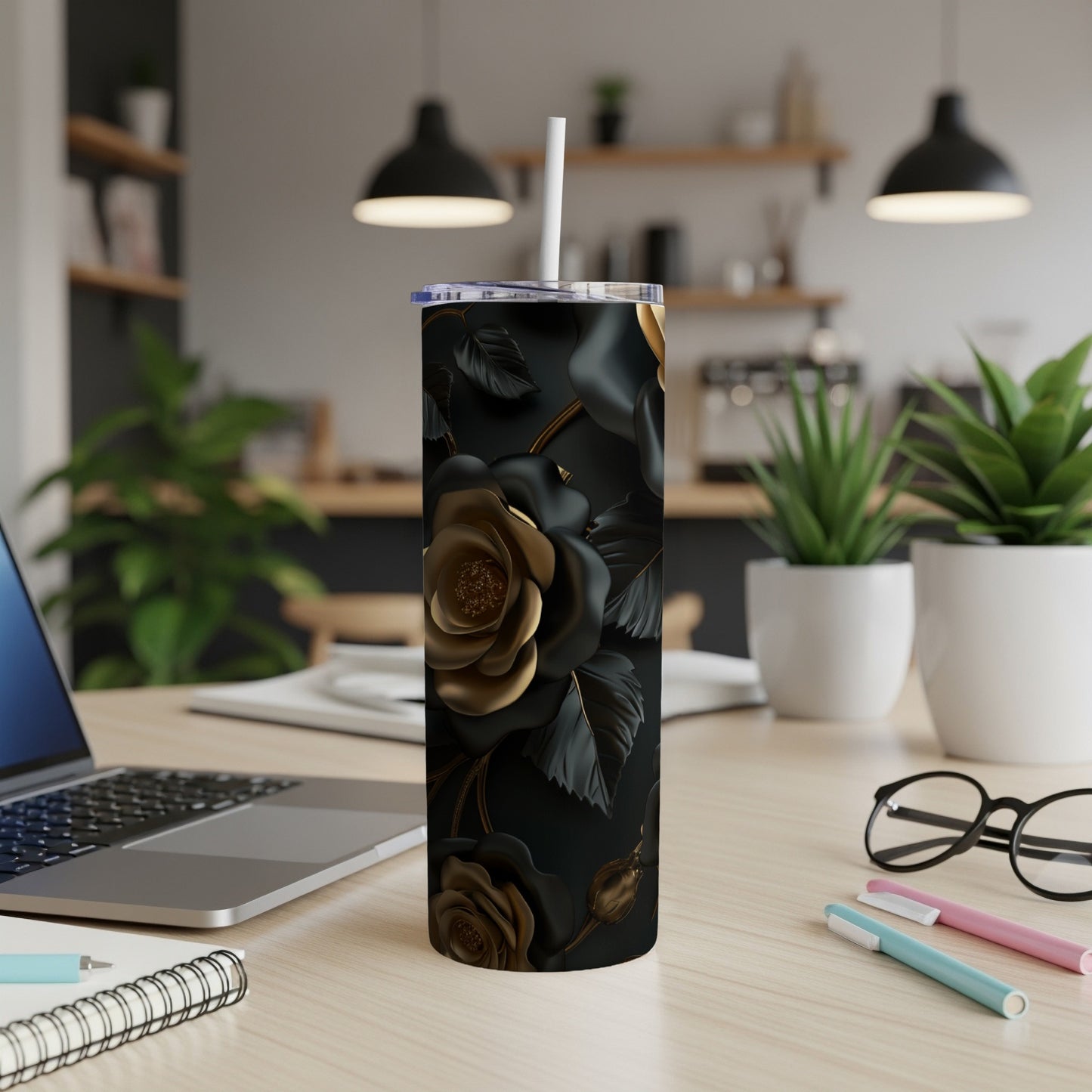 Black and gold floral tumbler with straw on a desk.