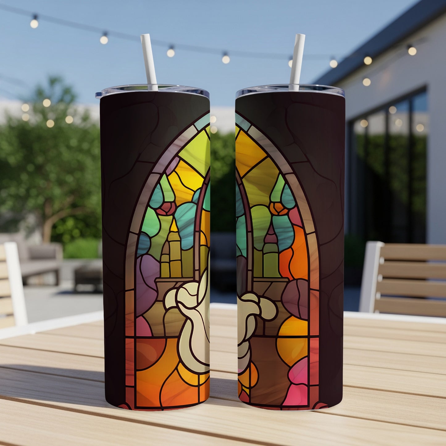 Stained glass design on two tumblers with straws on a patio table.