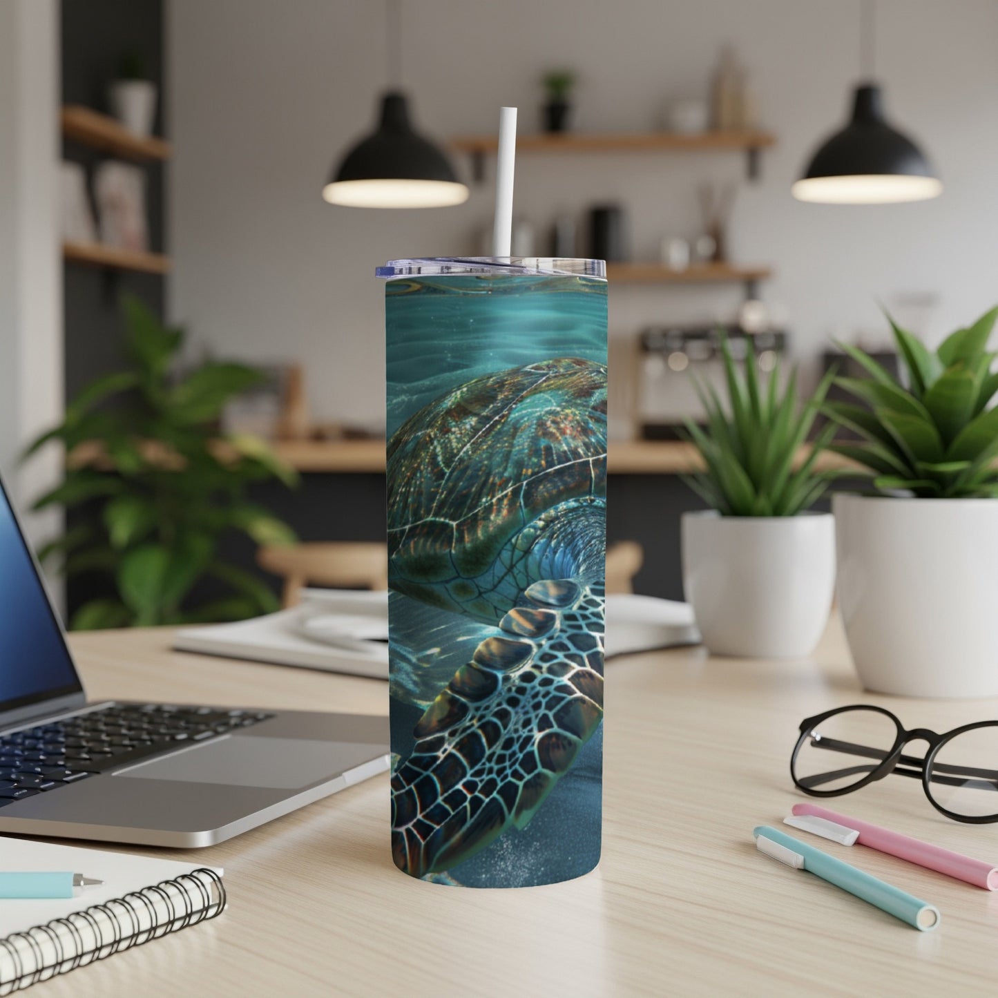 Sea turtle swimming underwater, design wraps around a white tumbler on a desk.