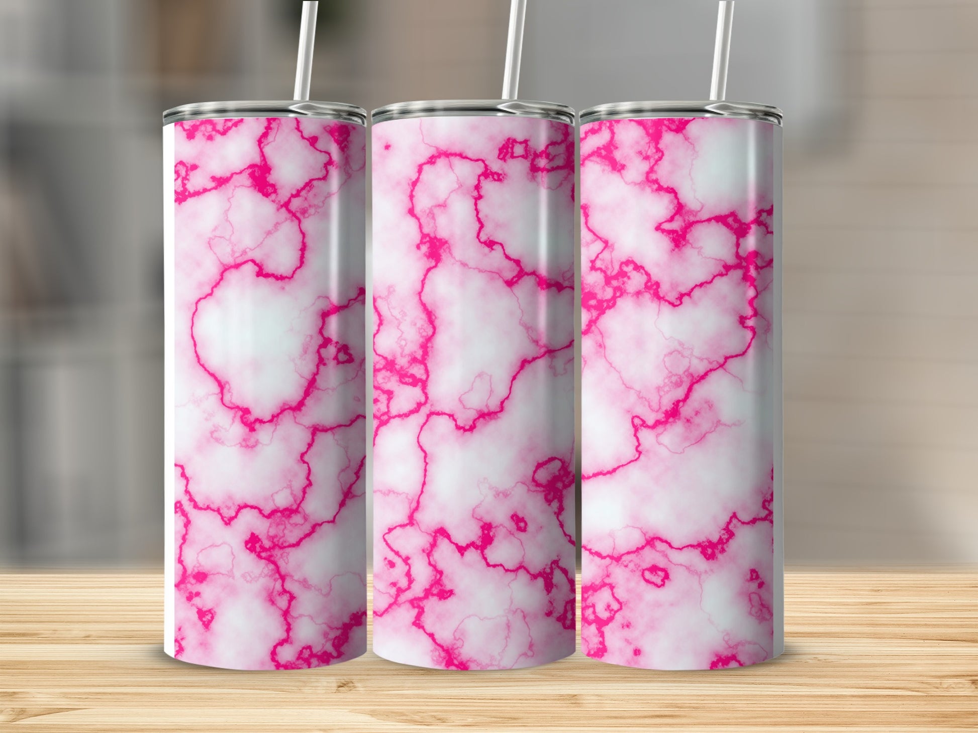 Three pink and white marble pattern tumblers with straws on a wooden surface.