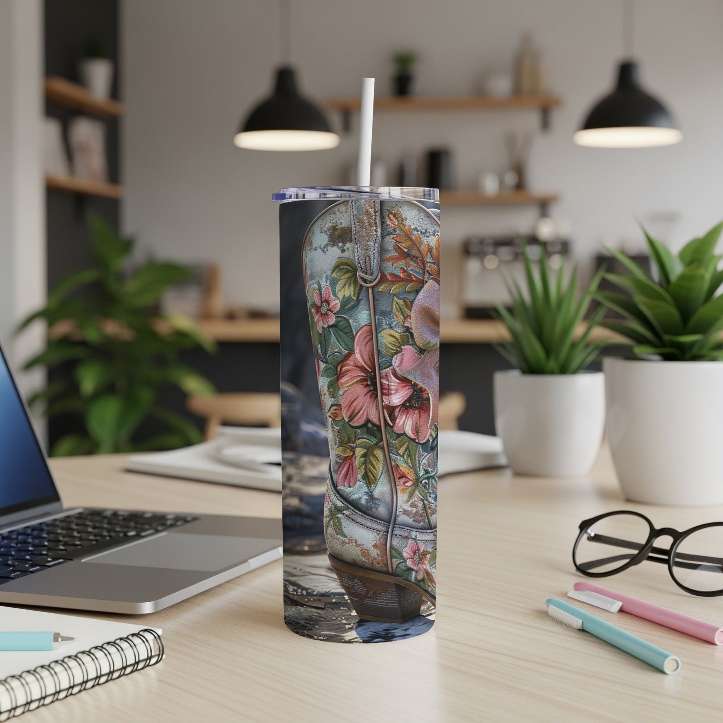 Cowboy boot tumbler with floral pattern on a wooden desk.