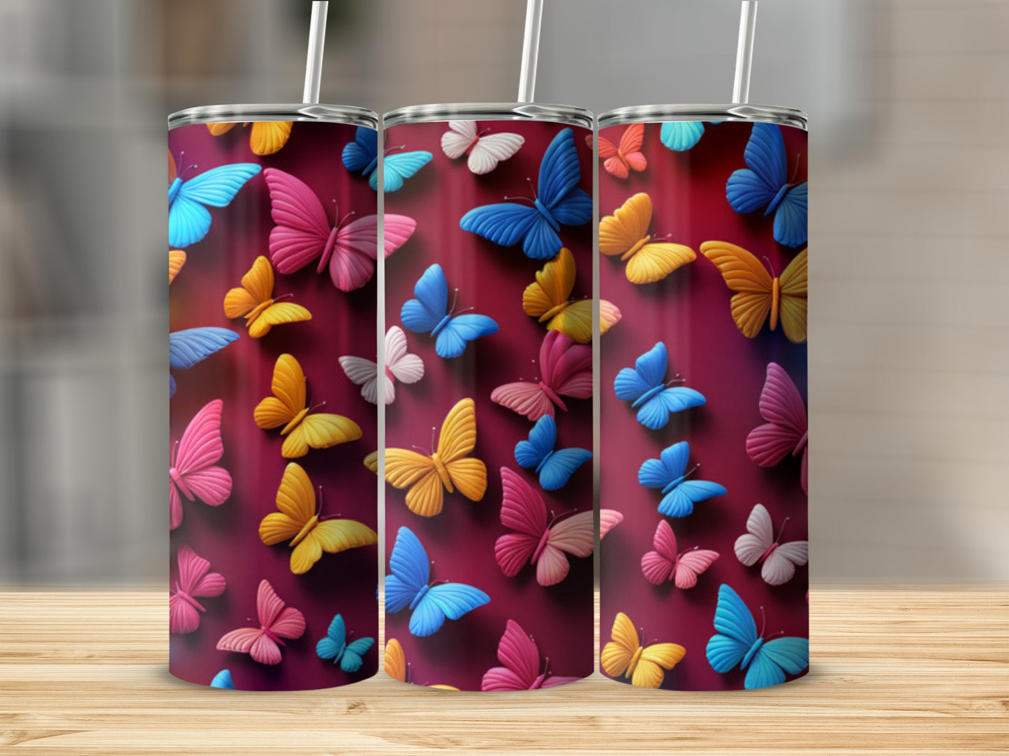 Three tumblers with colorful butterfly designs, arranged side-by-side.